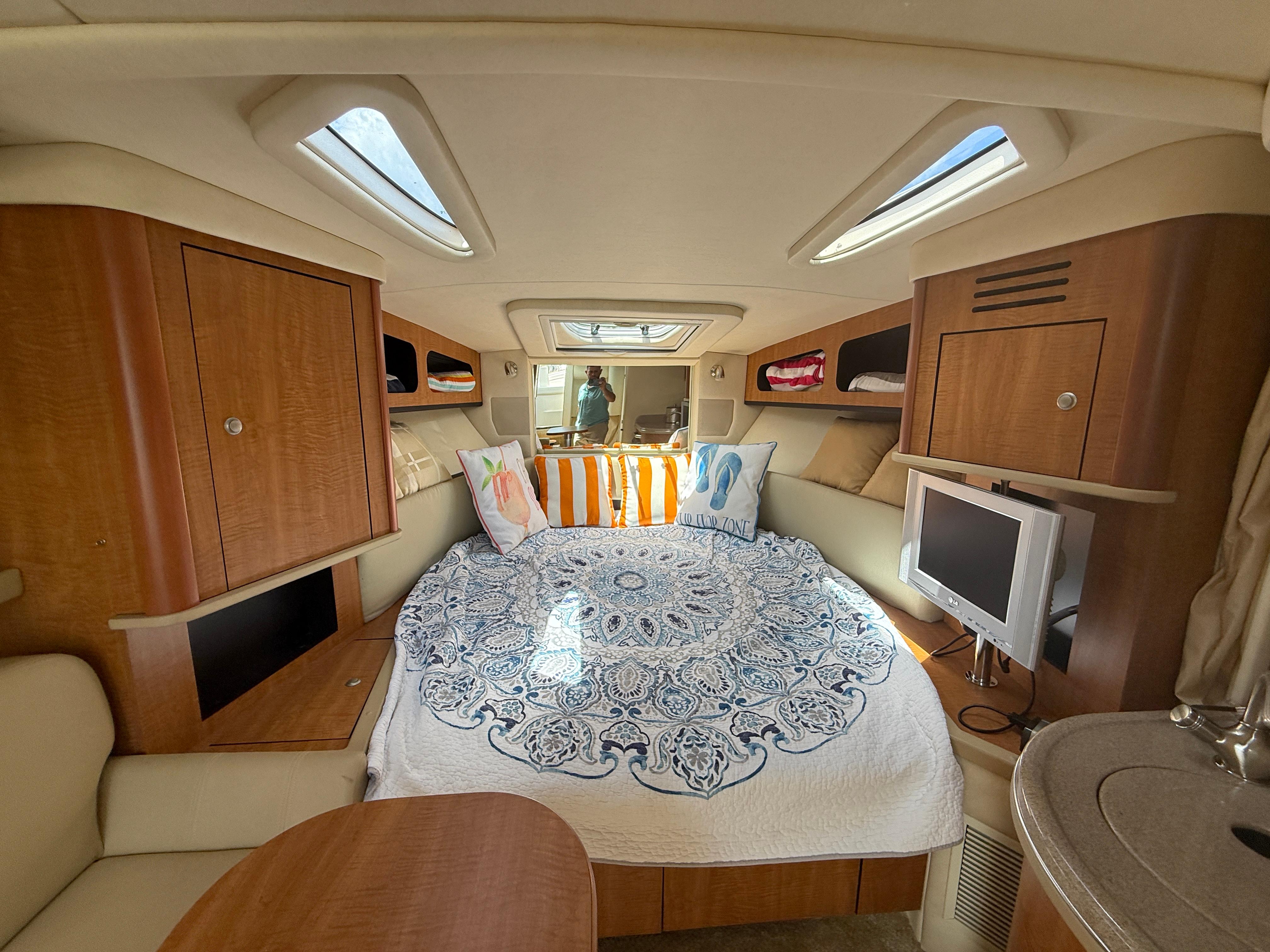 Interior of 2006 Sea Ray 290 Sundancer with cozy bed, TV, and wooden cabinetry.