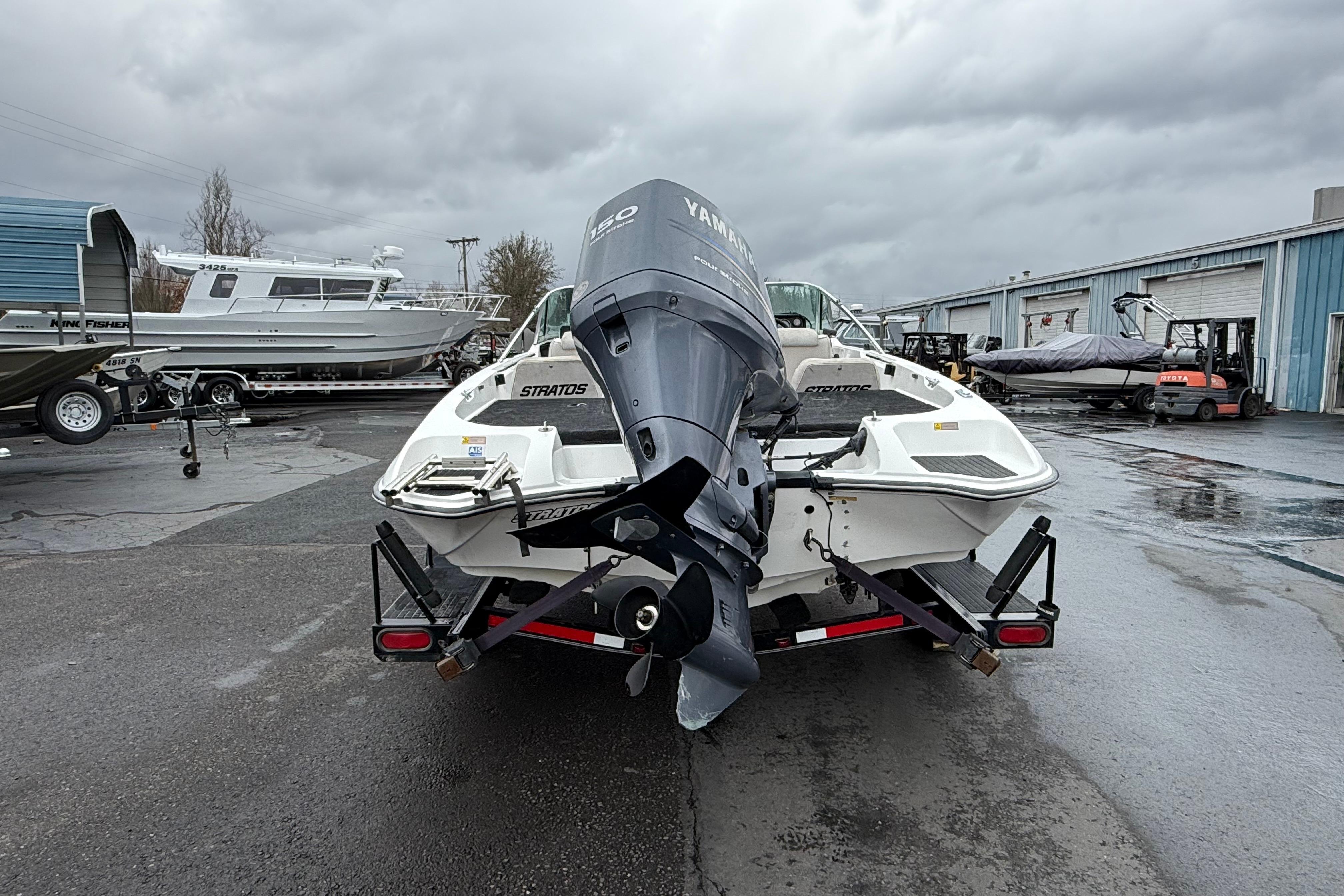 1996 Stratos 283 FS boat with Yamaha motor on trailer in a marina.
