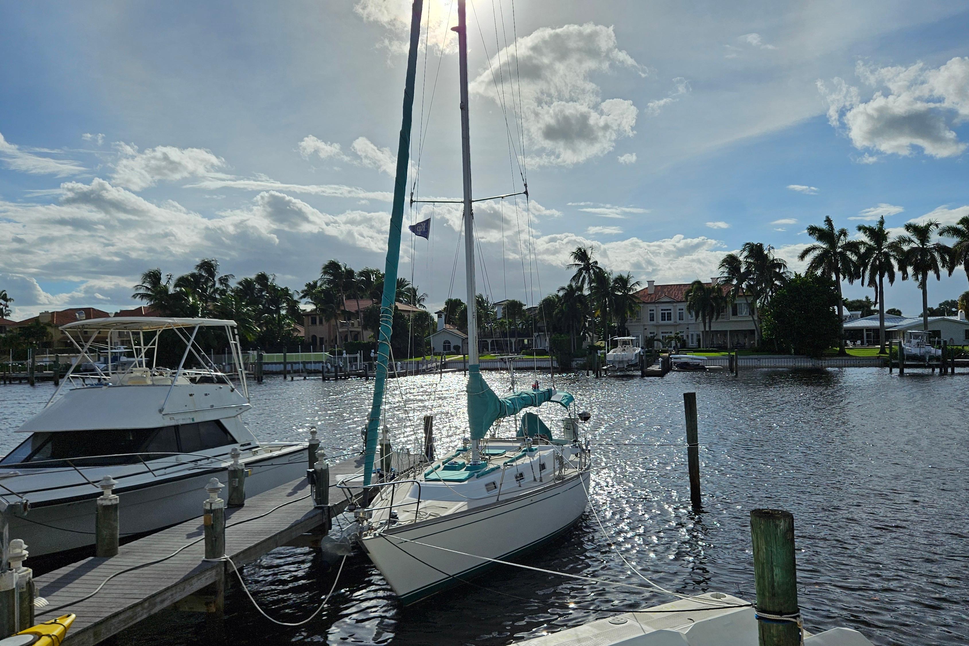Sailboat docked in sunny marina, Tartan 37 model, 1987, with palm trees in background.