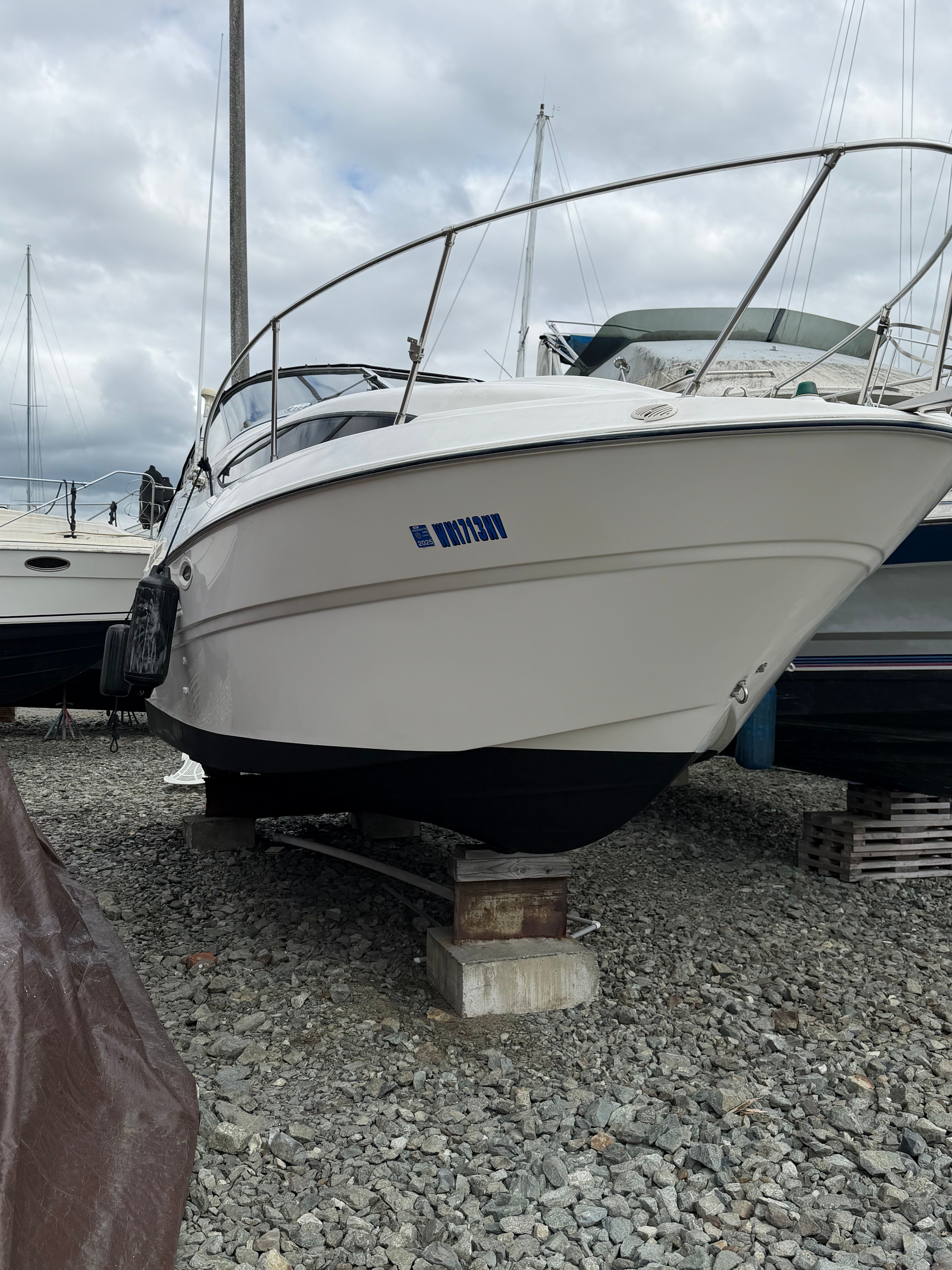 2005 Bayliner Cierra 245 on gravel, cloudy sky.