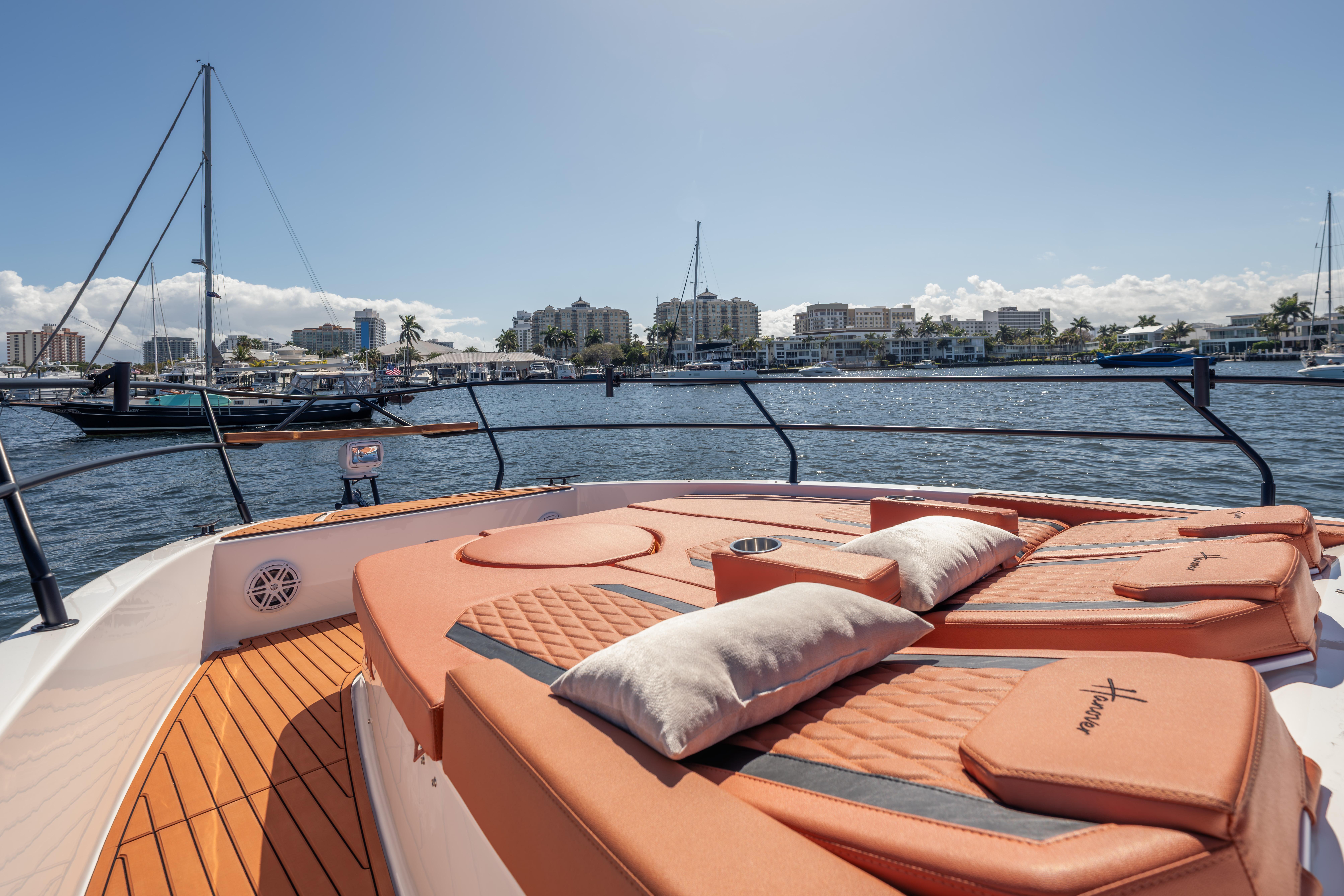 Luxurious 2026 Hanover 387 yacht with sunbathing deck, overlooking marina and city skyline.