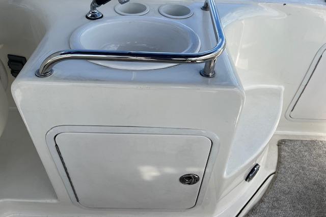 2003 Sea Ray 260 Sundancer boat sink and storage area with stainless steel rail.