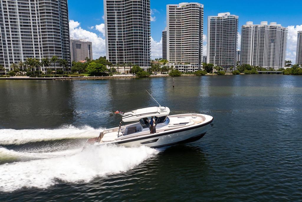 2021 Bluegame BG 42 yacht cruising near waterfront skyscrapers on a sunny day.