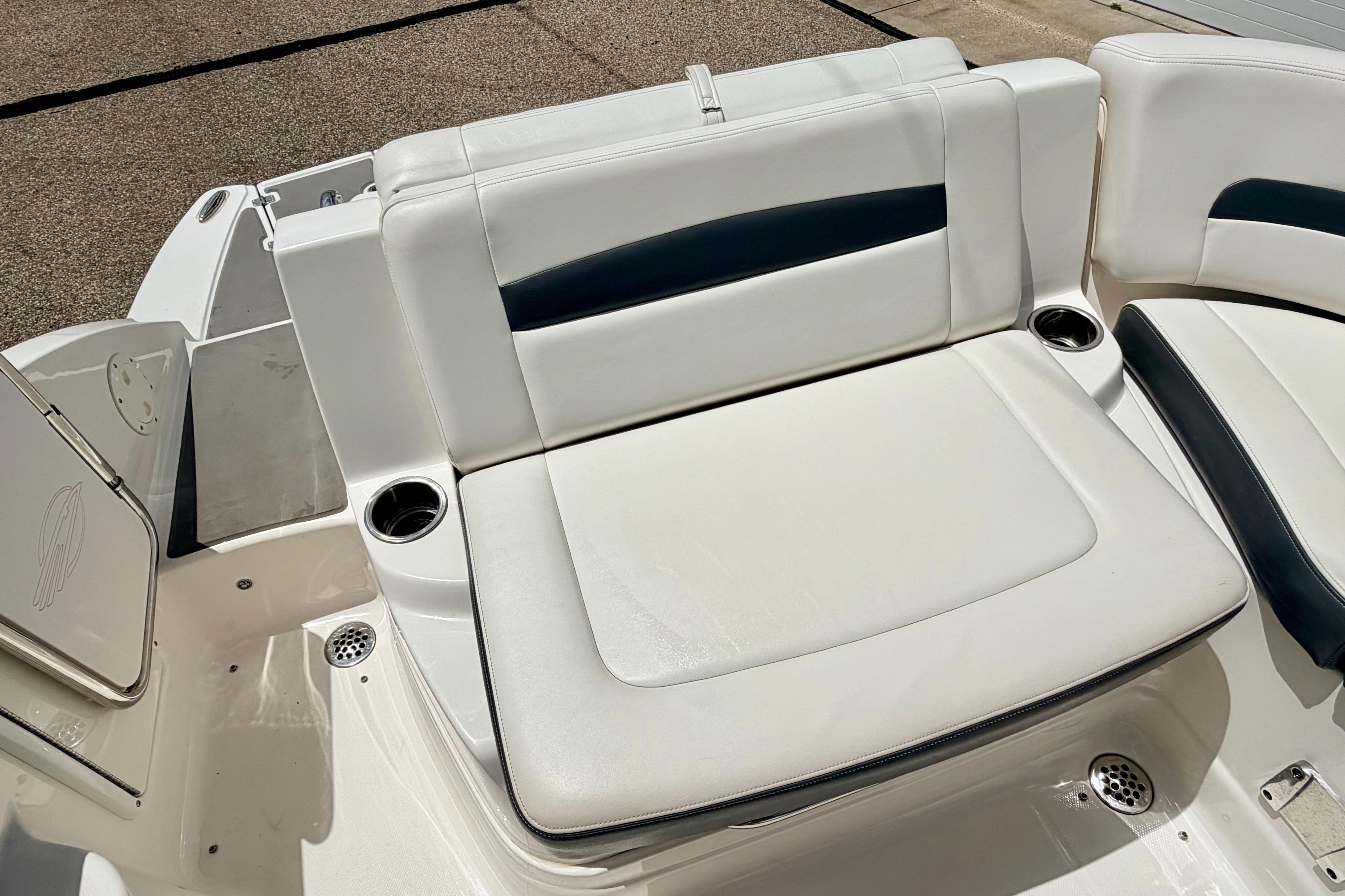 2015 Chaparral Sunesta 264 boat seating area with white upholstery and cup holders.