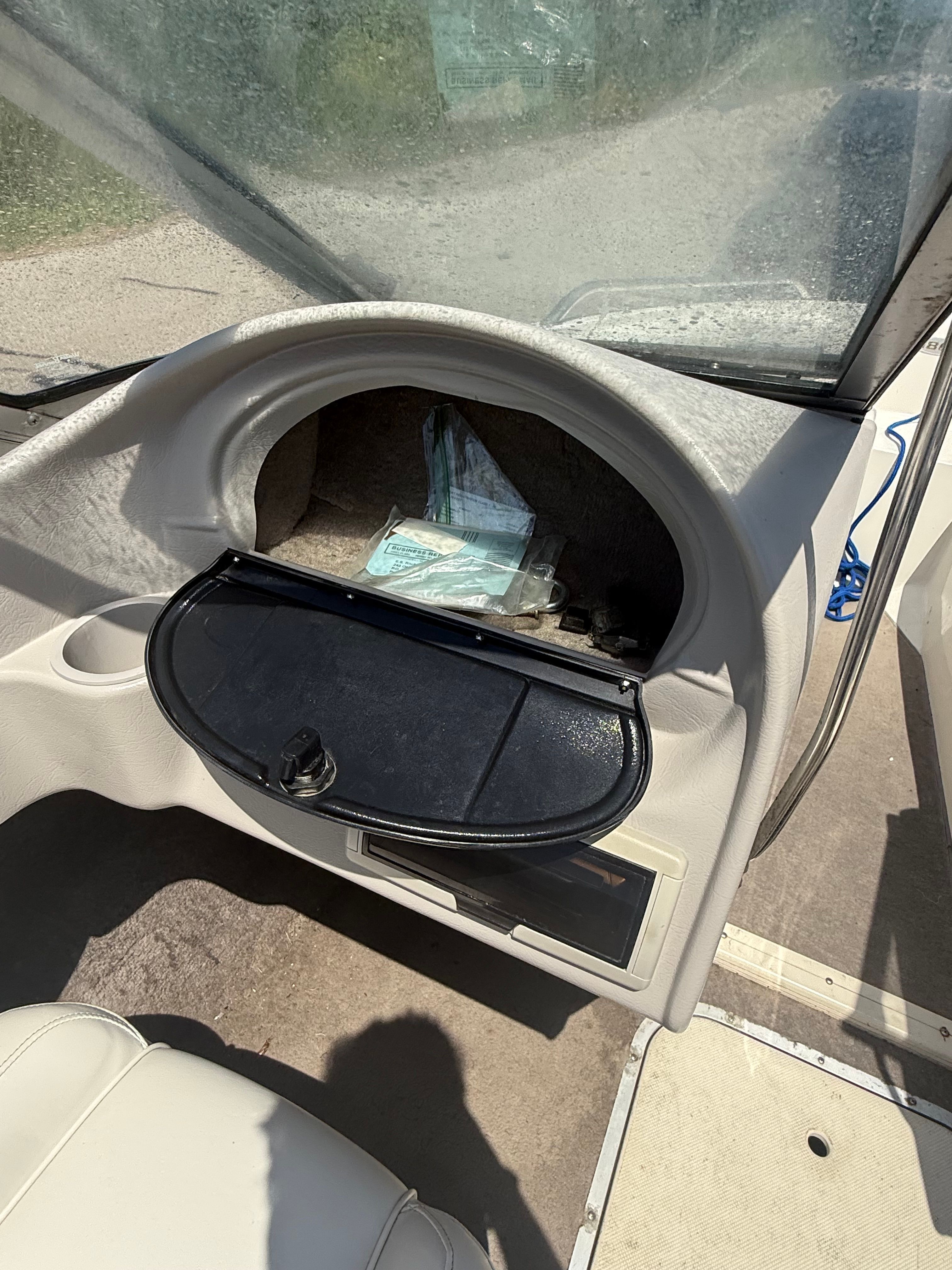 The image shows a boat's dashboard with an open glove compartment.