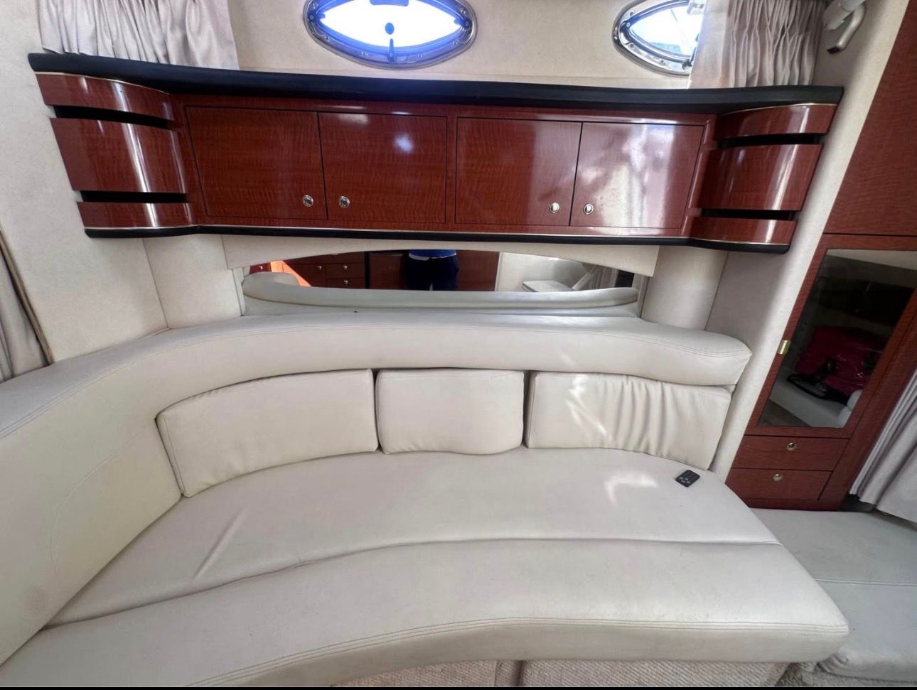 Interior of the 2002 Sea Ray 300 Sundancer with curved leather sofa and wooden cabinets.