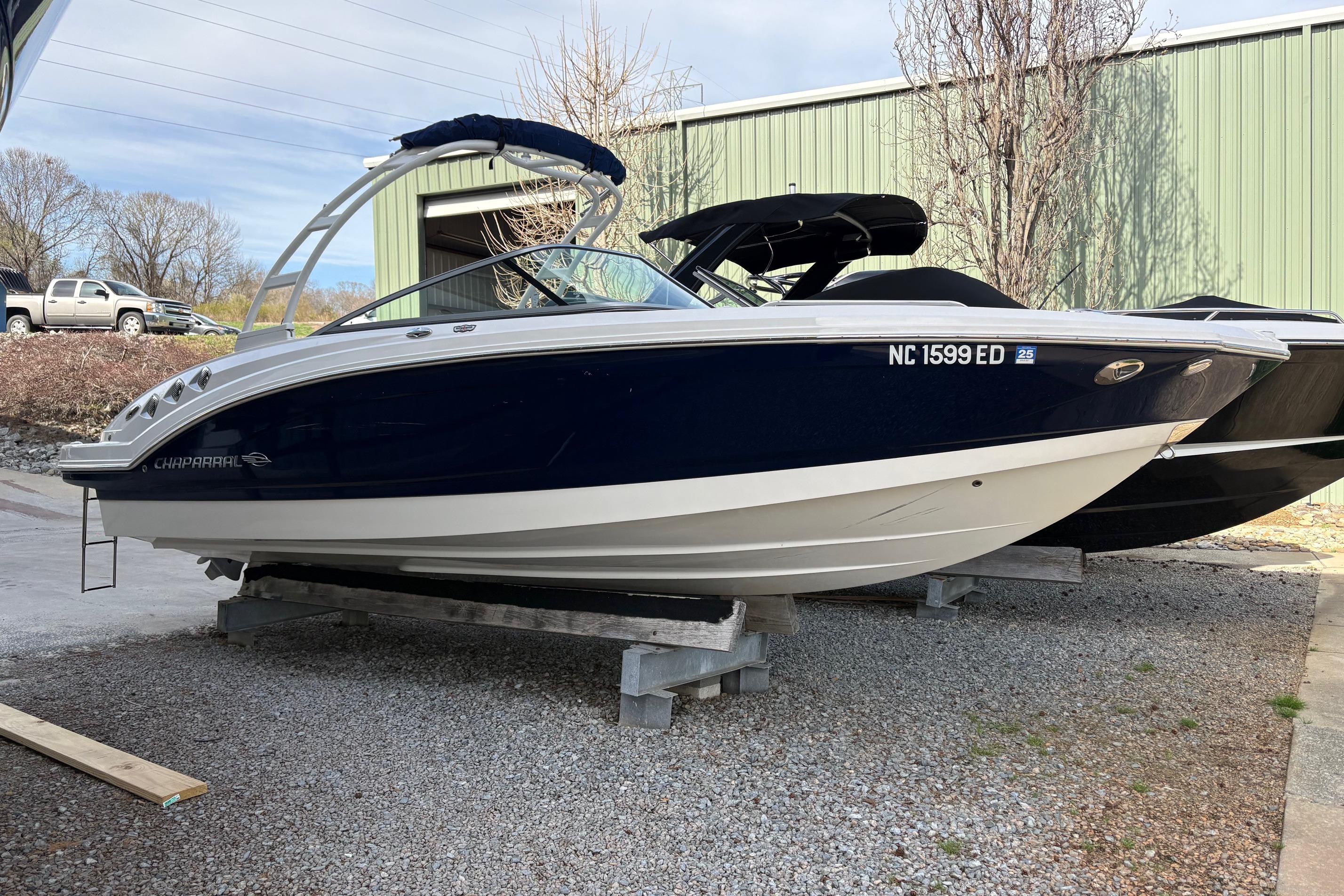 2016 Chaparral 246 SSi boat on display, blue and white hull, parked outdoors.