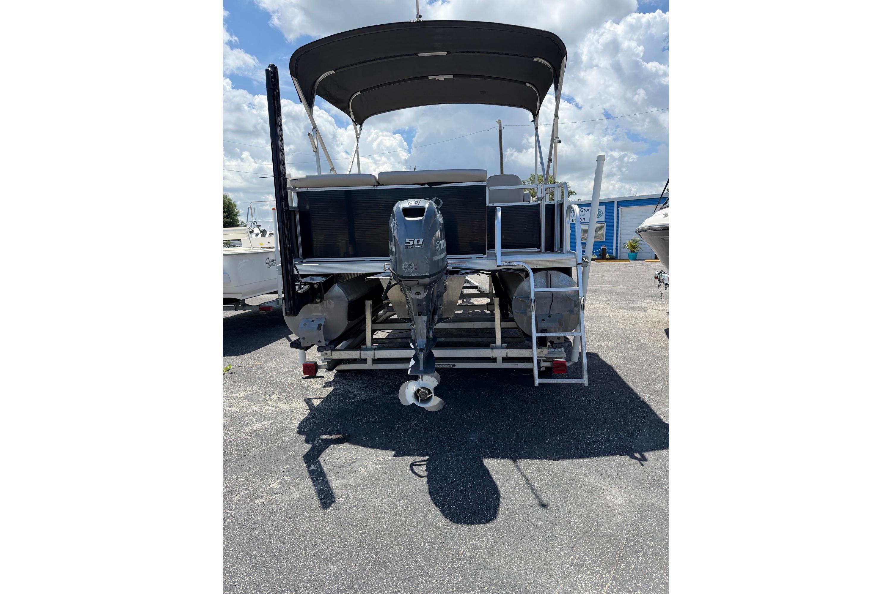 Rear view of a 2014 Avalon 1900 boat with an outboard motor, parked outdoors.