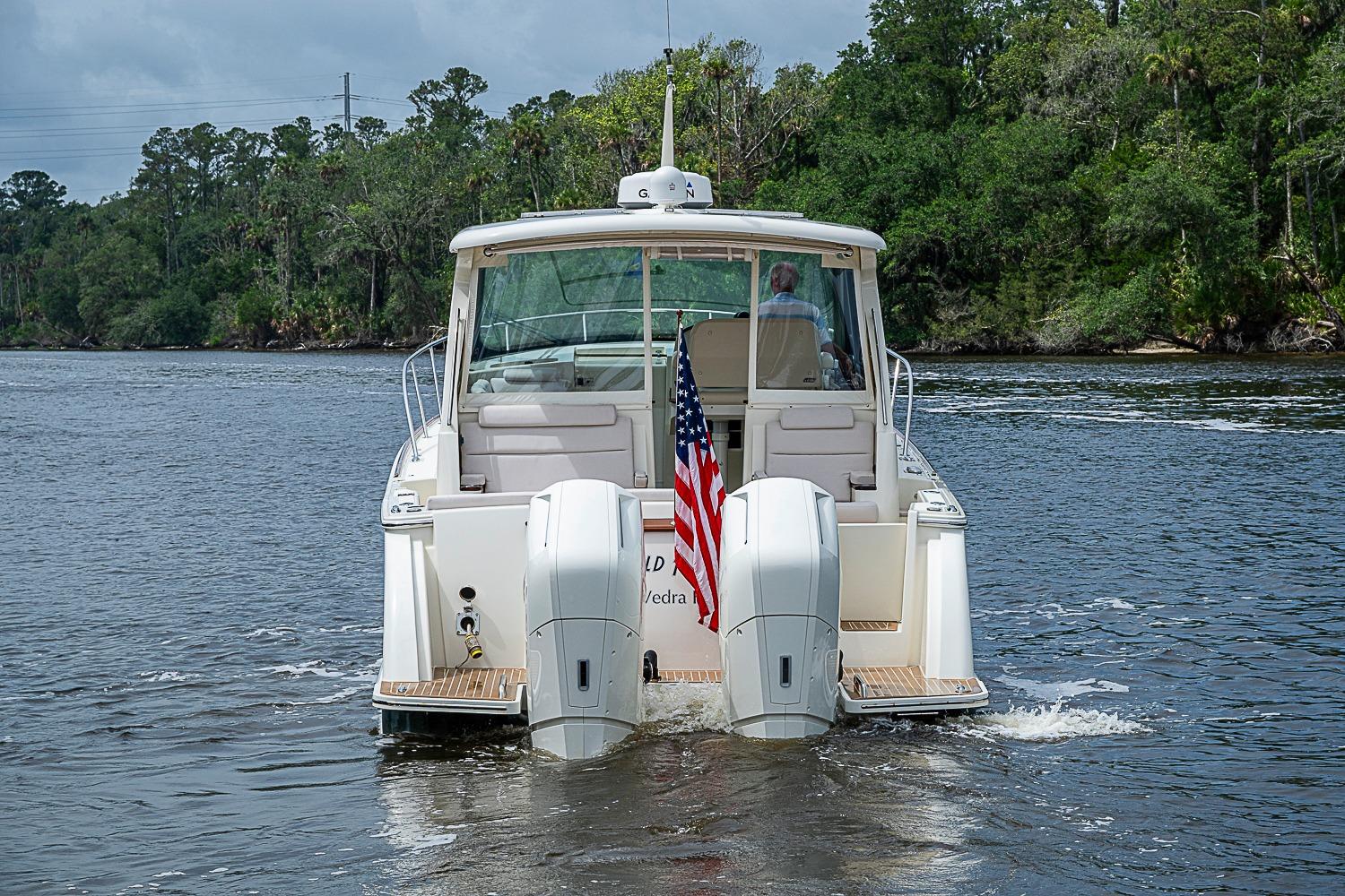 2023 Hinckley Sport Boat 40 X cruising on a scenic river with lush greenery.