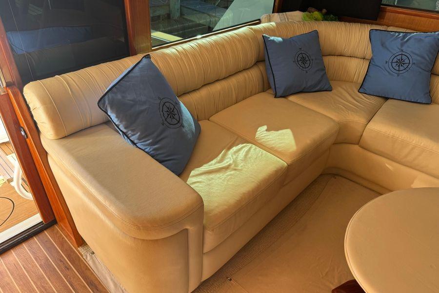 Luxurious beige leather seating with blue compass pillows on a 2002 Viking 61 Enclosed Bridge yacht.
