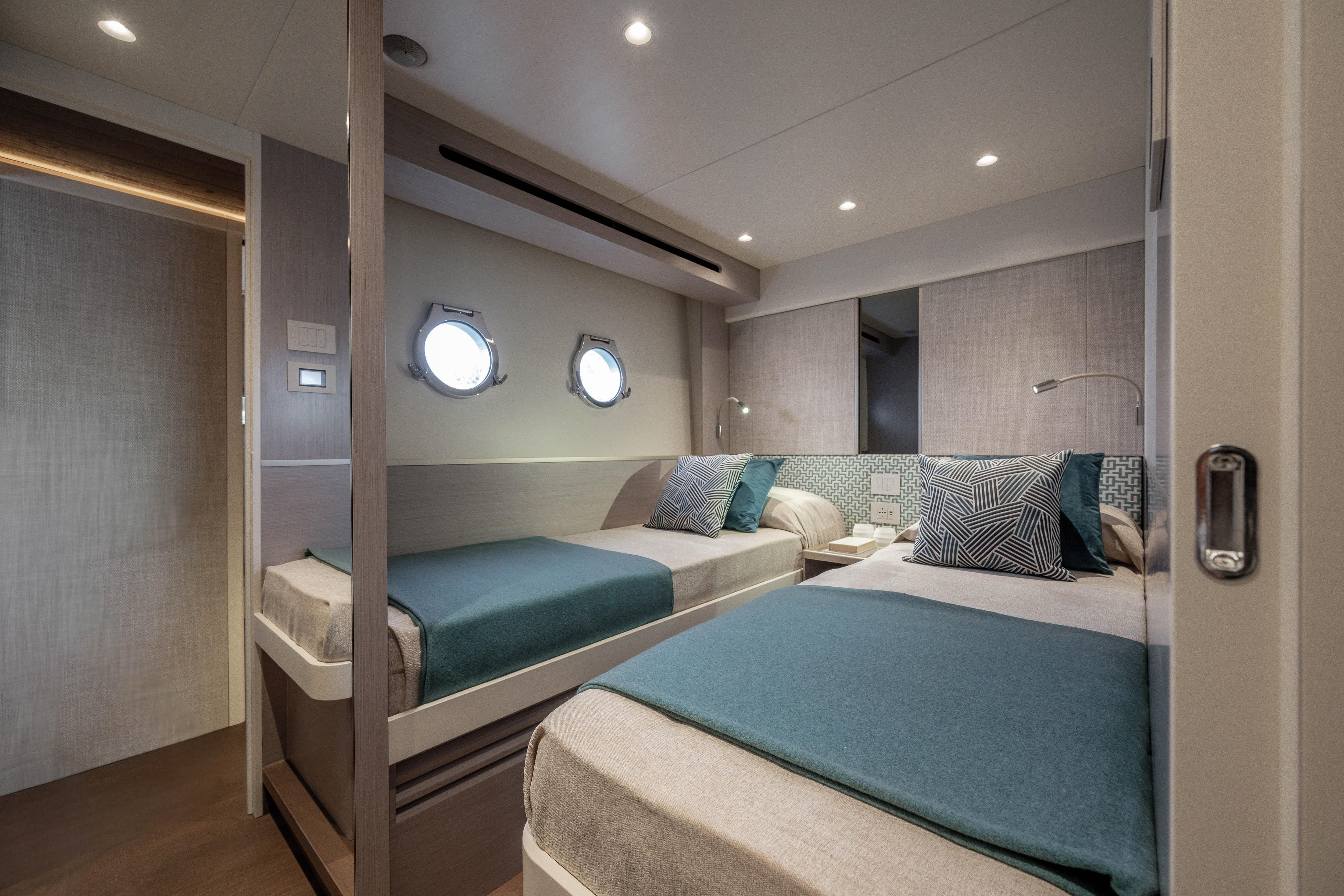 Elegant bedroom on a yacht with two single beds and porthole windows.