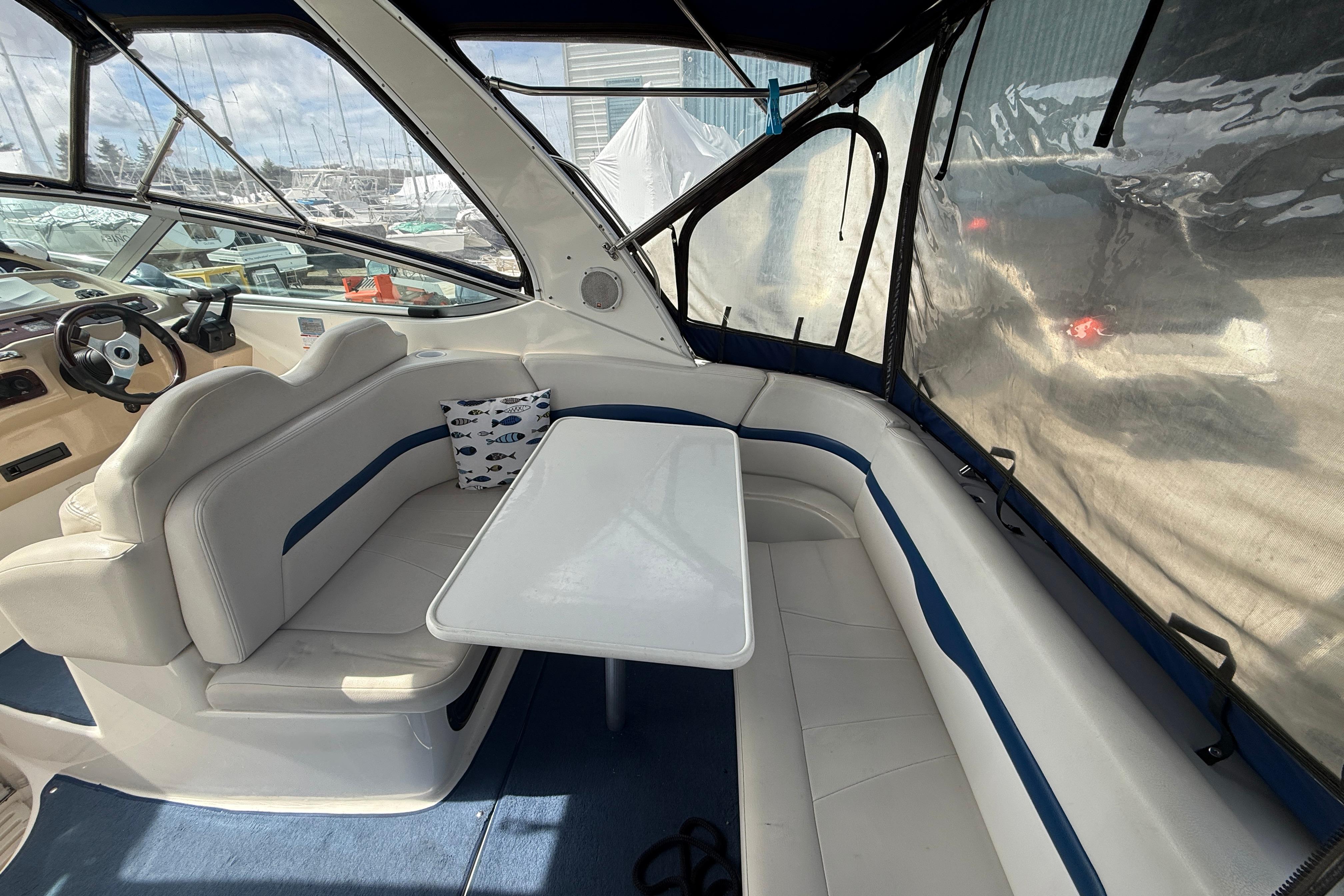 2003 Chaparral Signature 280 boat interior with seating and table, featuring a nautical-themed pillow.