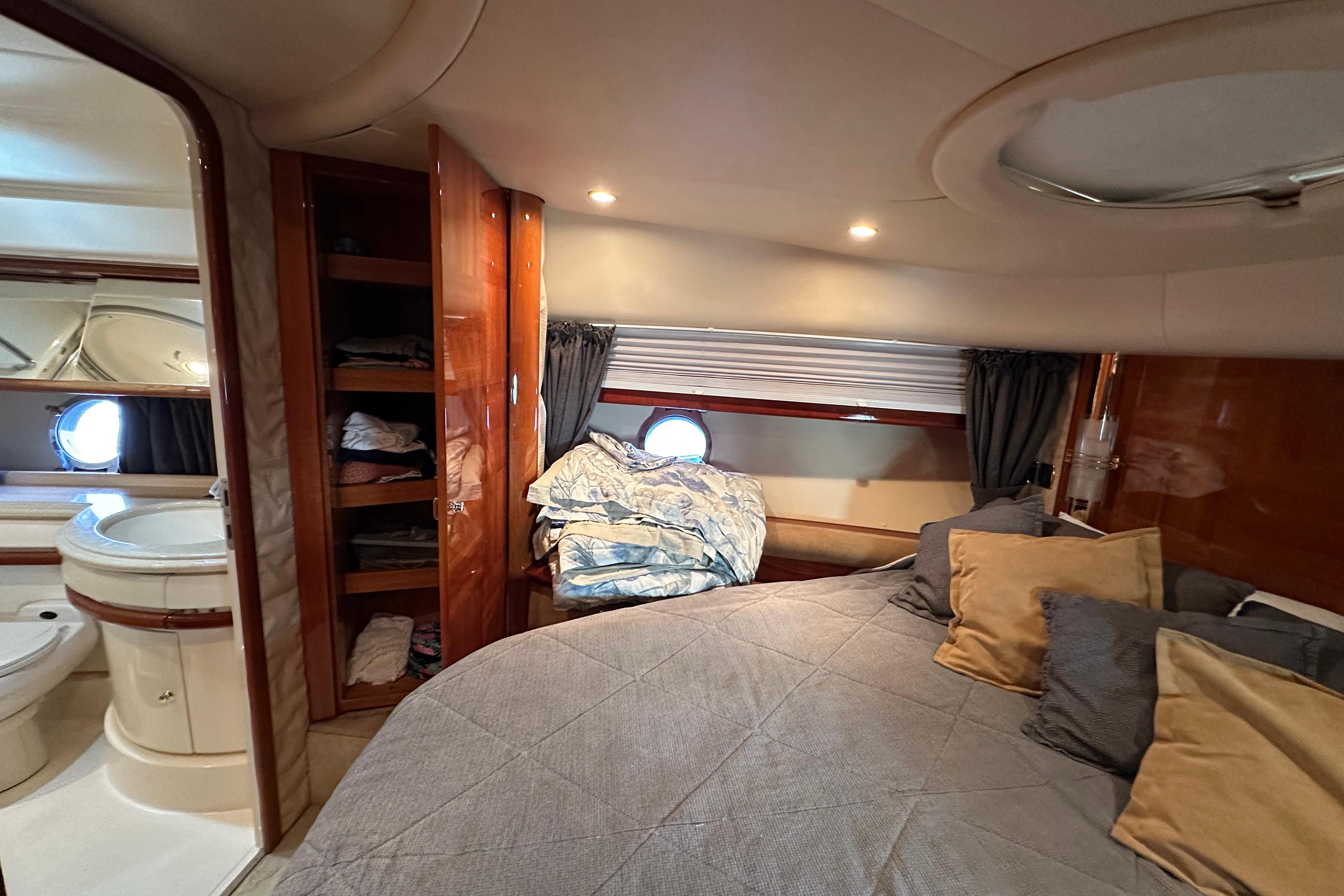 Luxurious cabin interior of a 2004 Azimut 55E yacht with cozy bedding and elegant wood finishes.