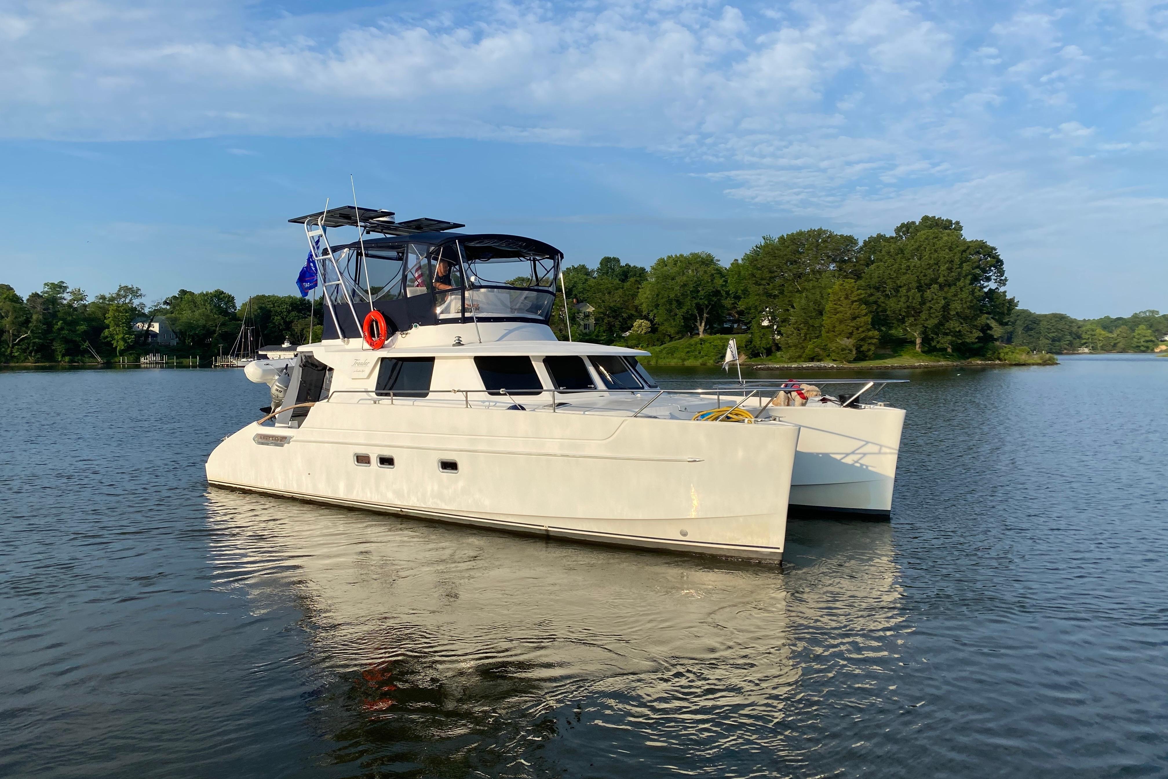 2005 Fountaine Pajot Maryland 37 catamaran on calm water, surrounded by lush greenery.