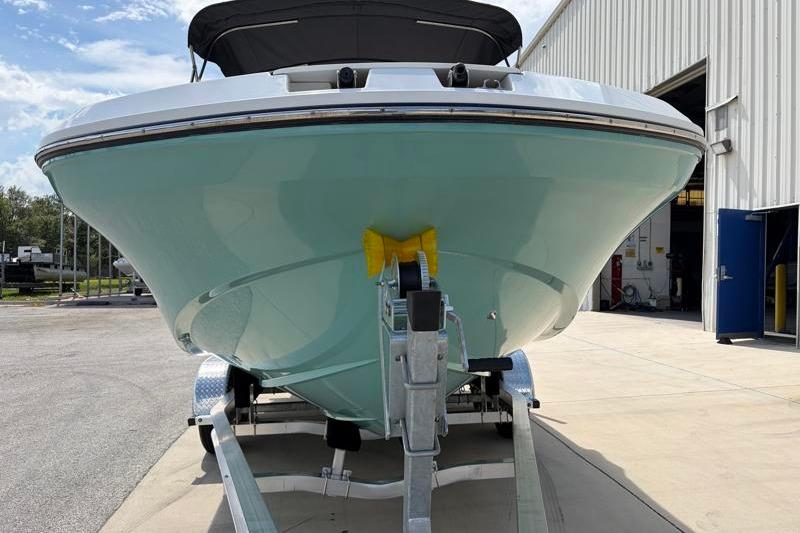 2026 Hurricane SunDeck Sport 2050 OB boat on trailer outside a warehouse.