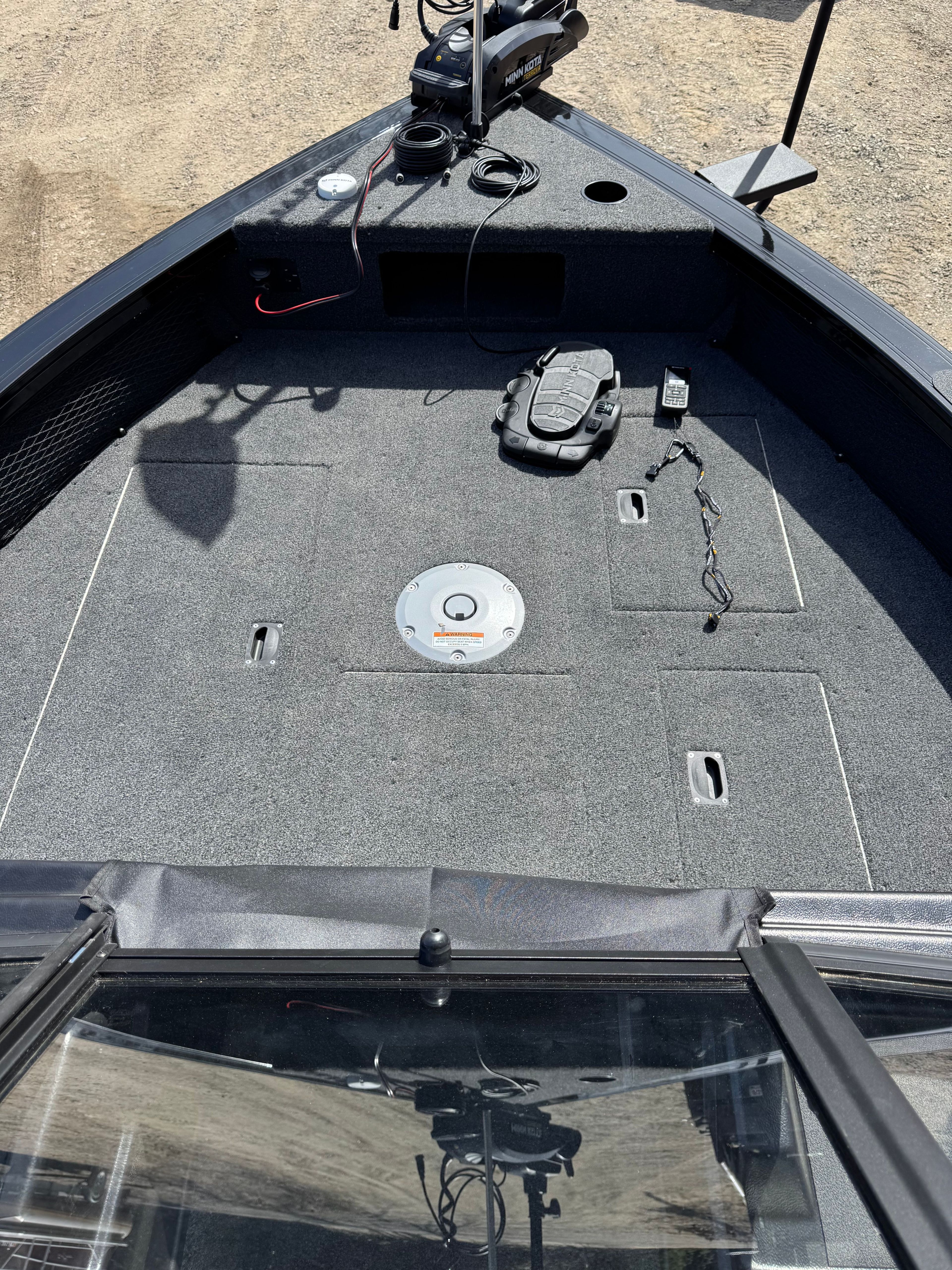 The boat features a spacious deck with gray carpeting and fishing equipment.
