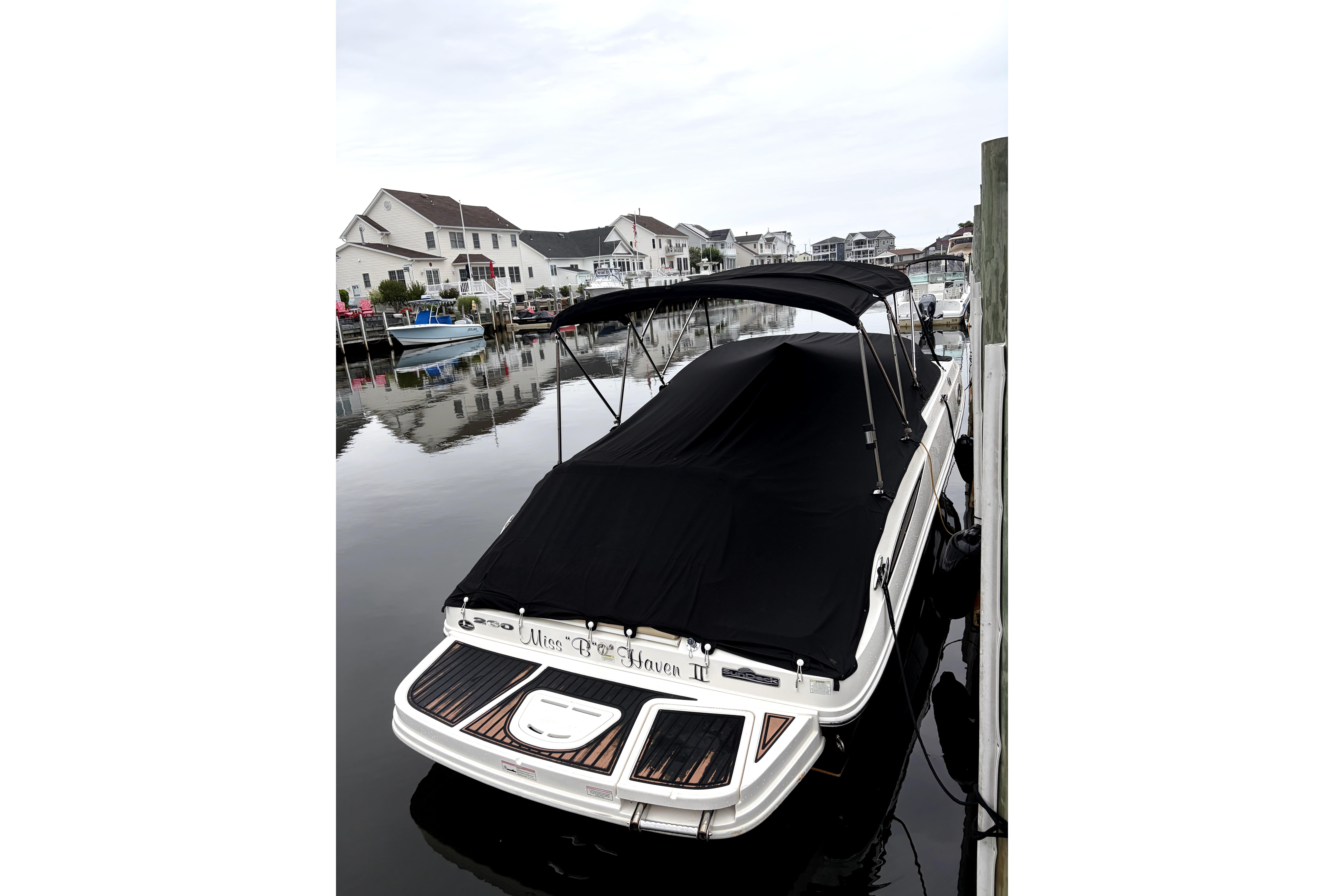 2014 Sea Ray 260 Sundeck boat docked with black cover in a residential marina.