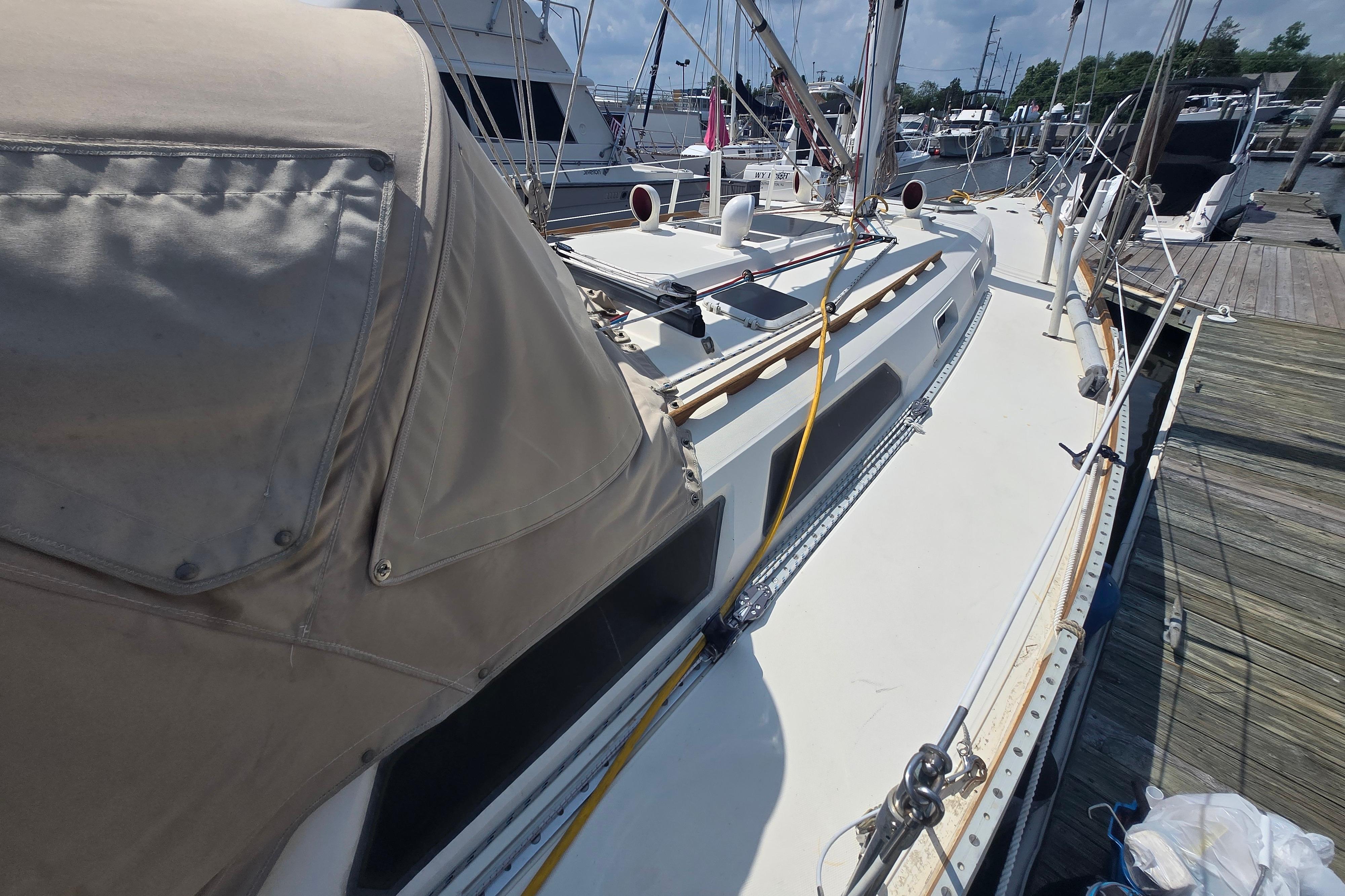 1988 Sabre 38 sailboat docked at marina, featuring beige canopy and clean deck.