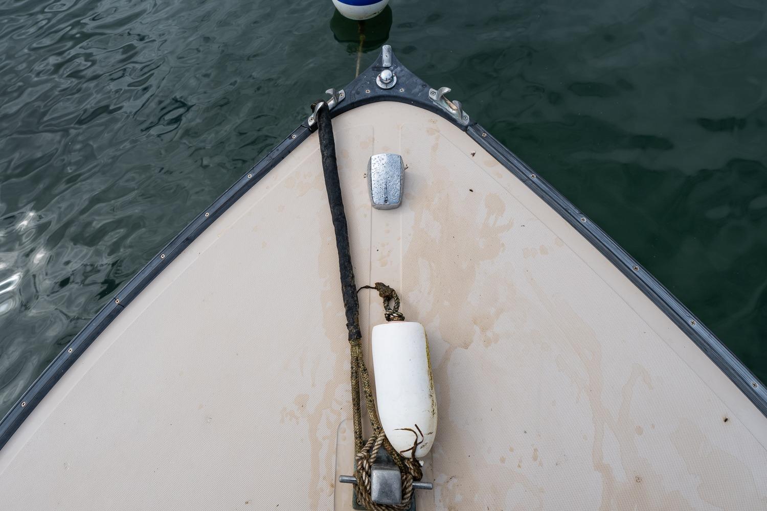 Bow of 1989 Ellis 24 Open boat with rope and buoy on water.
