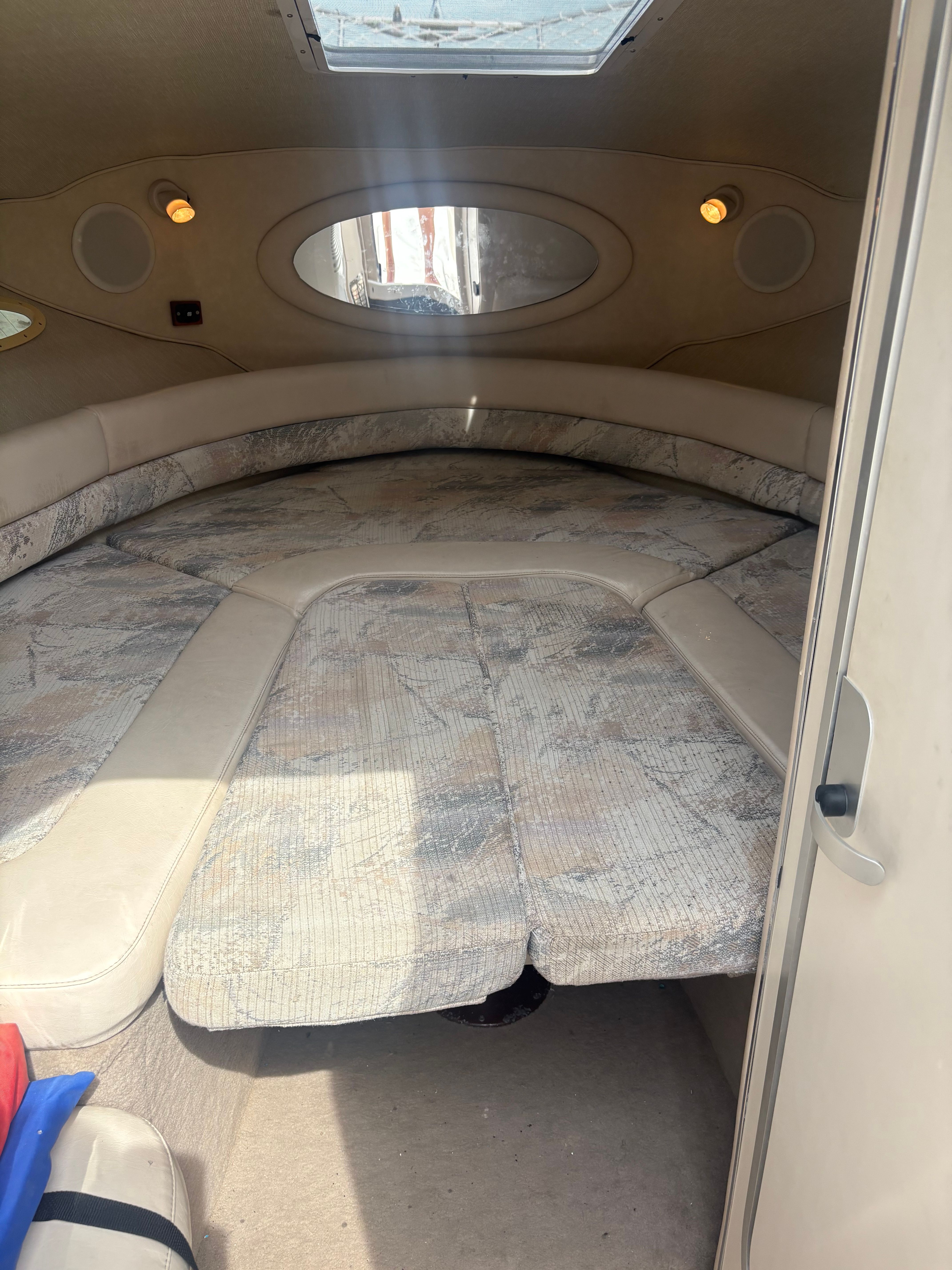 Interior view of a 1996 Sea Ray 280 Cuddy Cabin with cushioned seating and a porthole.
