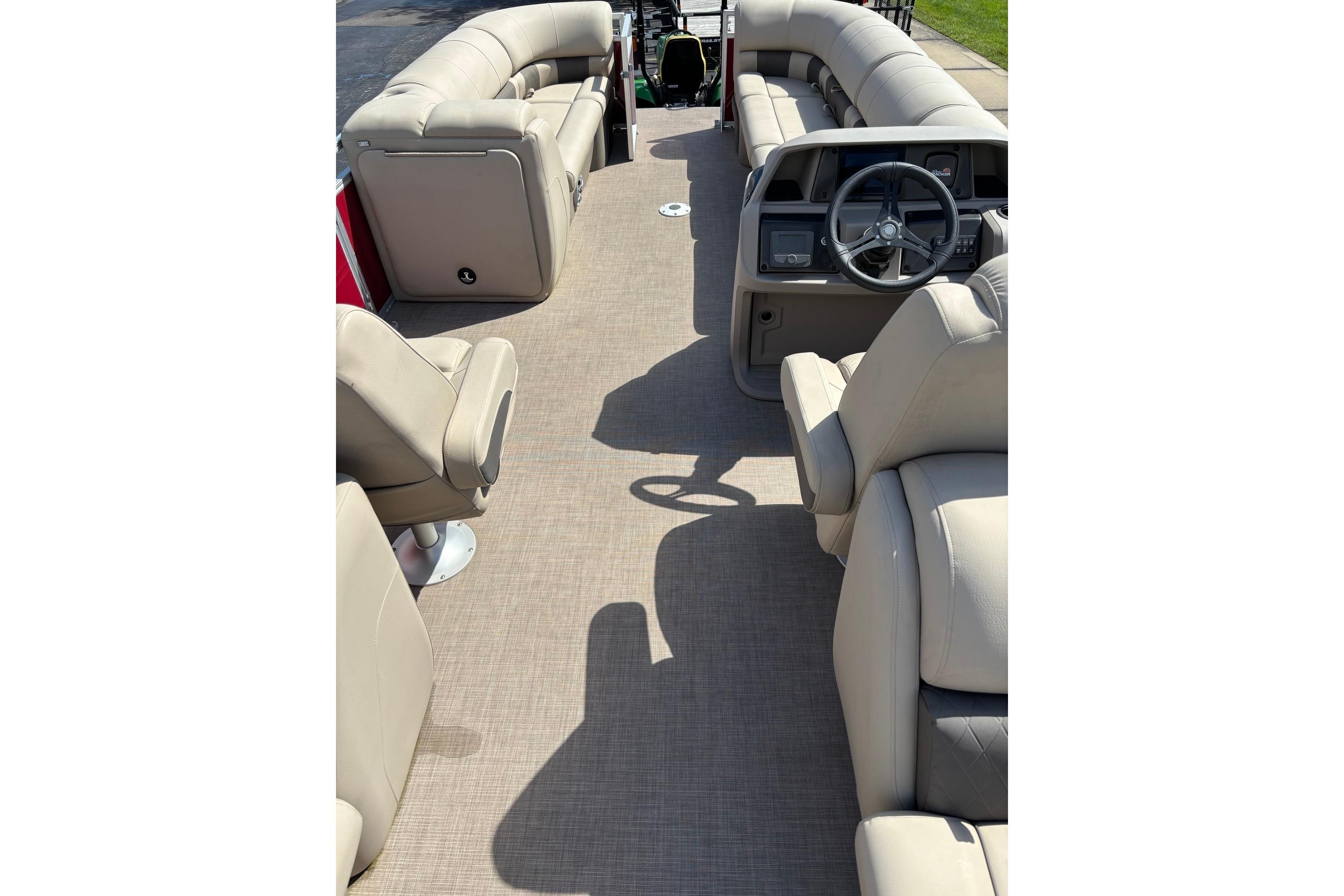 2024 Sun Tracker Party Barge 24 DLX interior with beige seating and steering console.