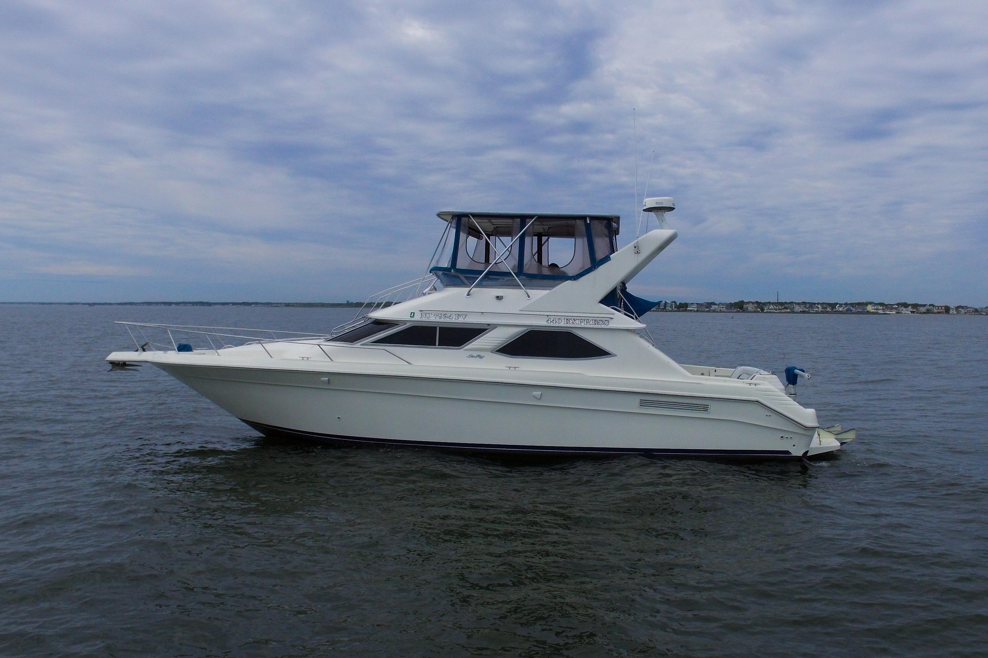 1993 Sea Ray 440 Express Bridge yacht on calm waters under a cloudy sky.