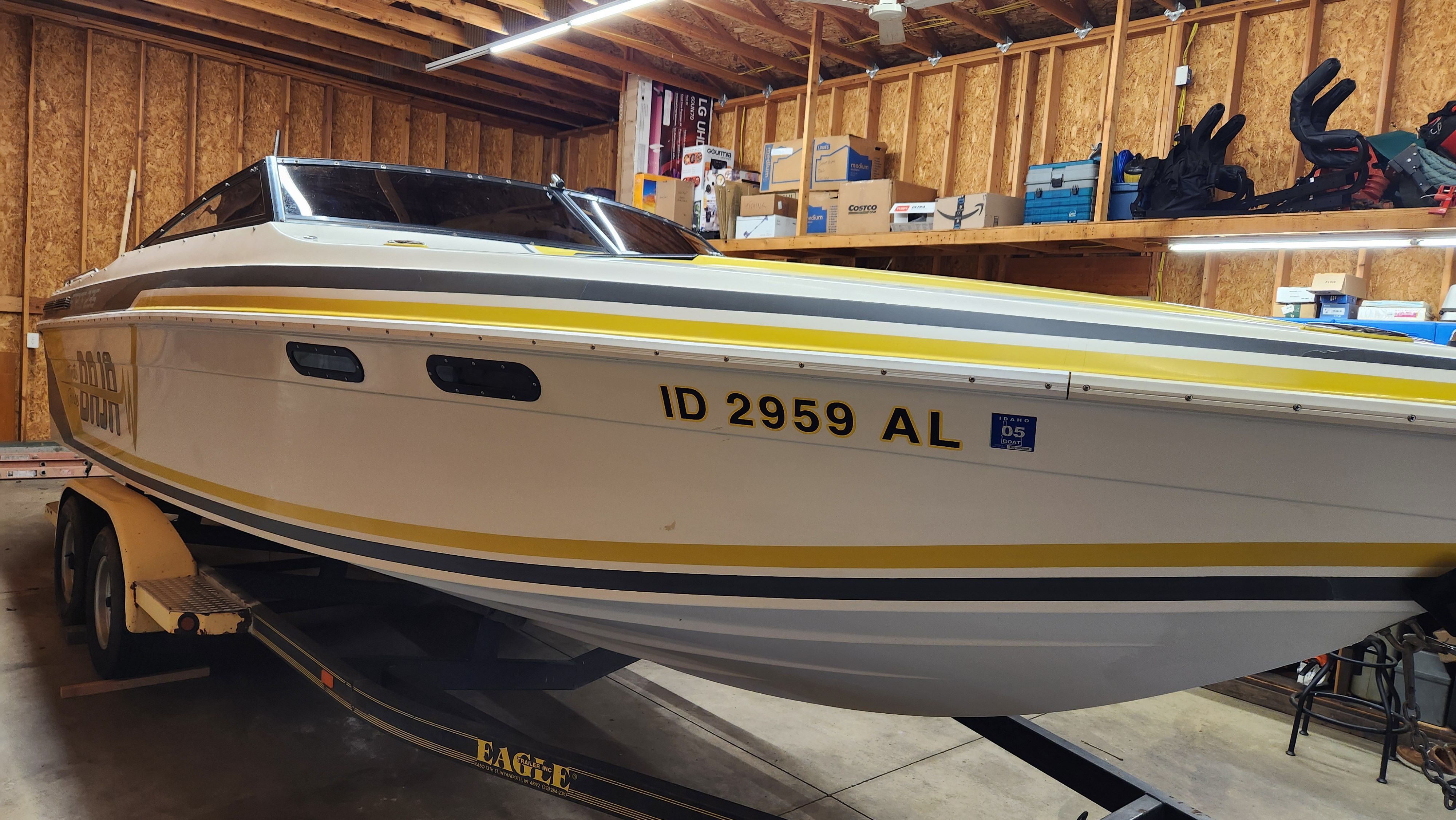 A 1989 Baja FORCE 235 boat on a trailer in a garage.