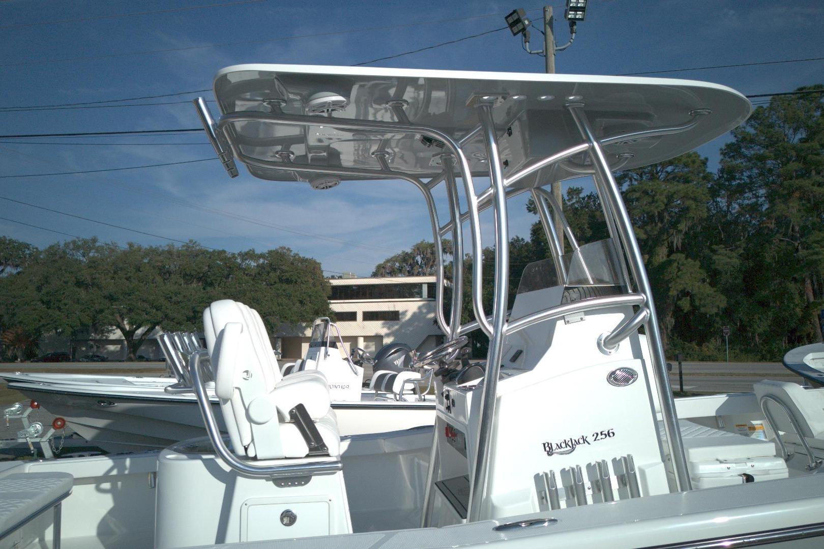 2026 BlackJack 256 Coastal boat with T-top and seating, parked outdoors.