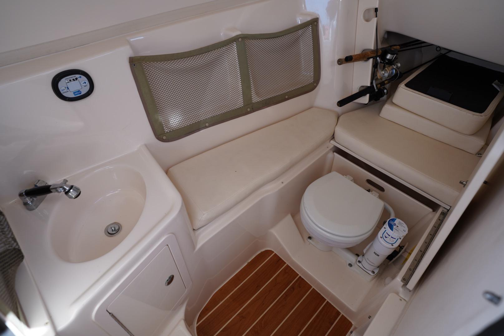 2015 Grady-White Freedom 307 boat interior with sink, toilet, and seating area.