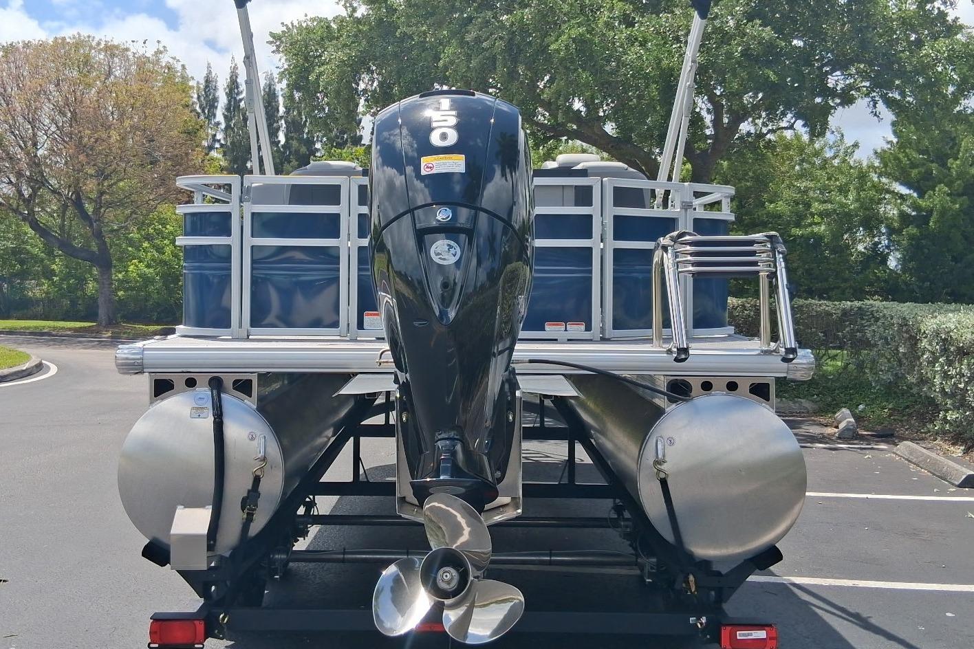2026 Sun Tracker SportFish 22 DLX pontoon boat with powerful outboard motor, parked outdoors.