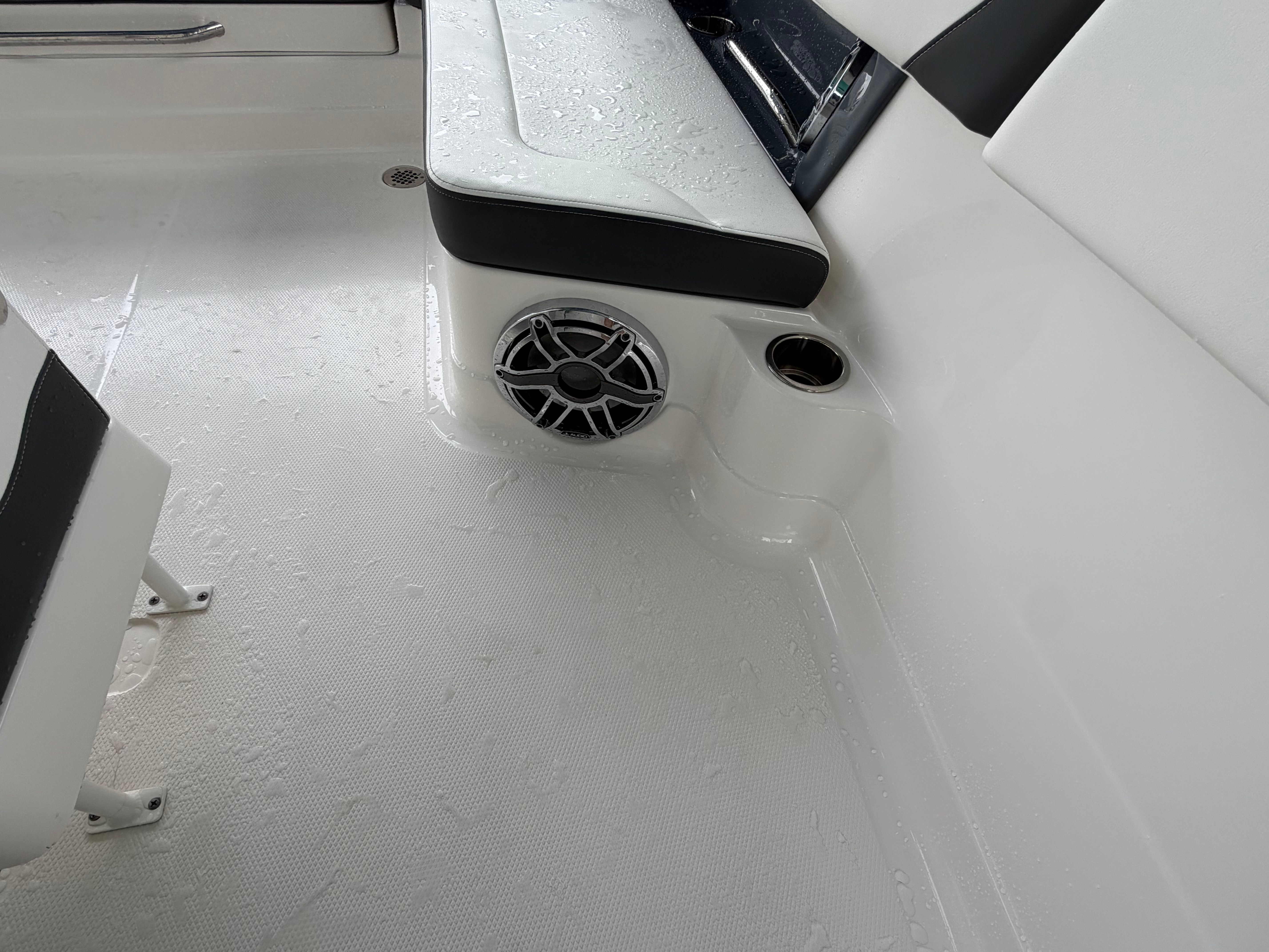 Close-up of a boat interior with white seating and a speaker.