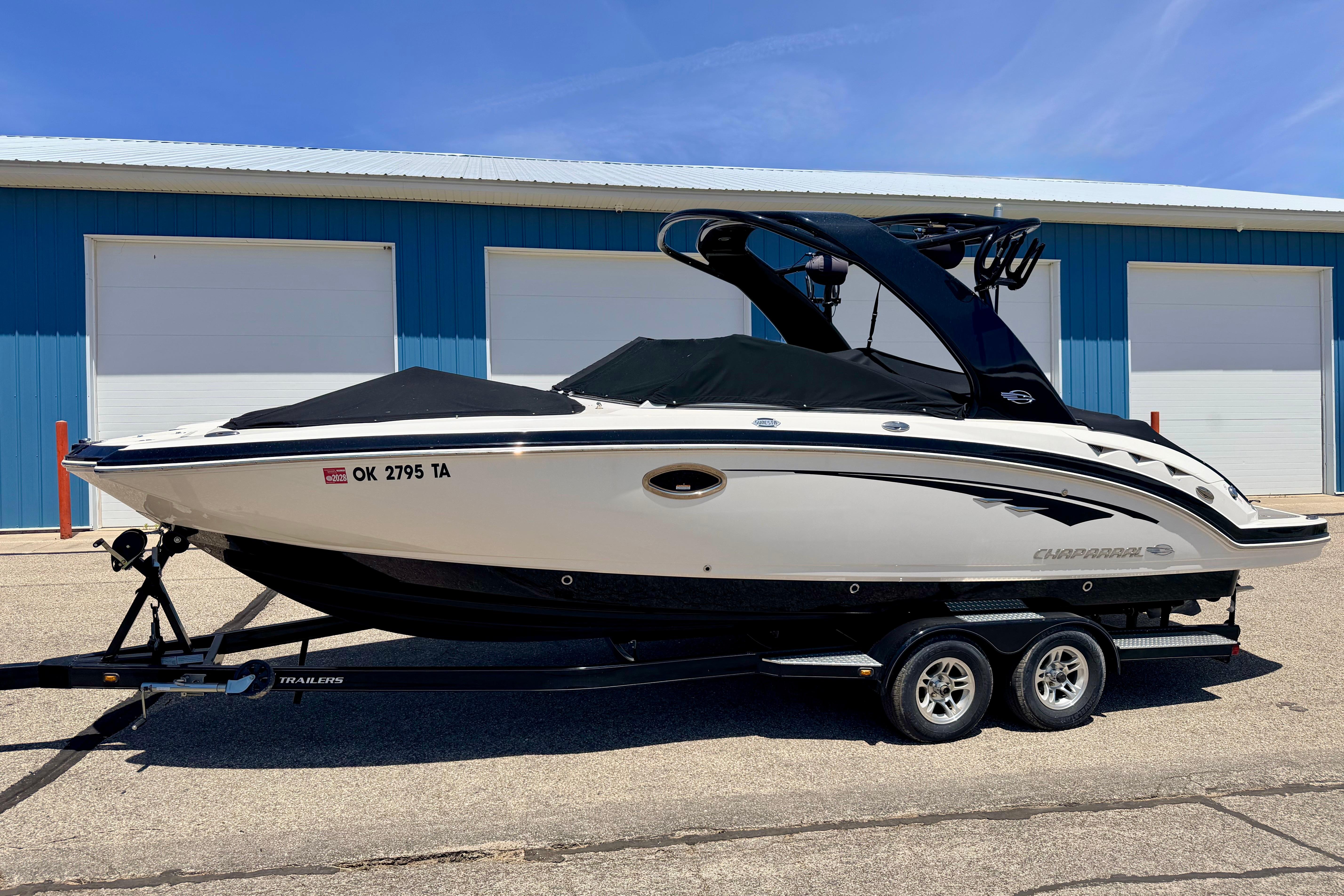 2015 Chaparral Sunesta 264 boat on trailer, parked outside blue warehouse.
