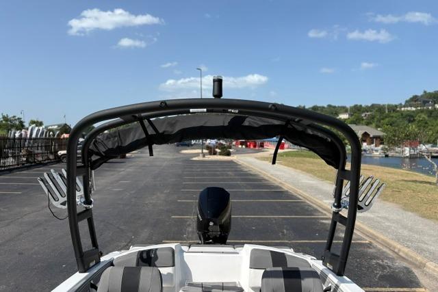 2024 Tahoe T21 boat with canopy, parked near a marina under a clear blue sky.