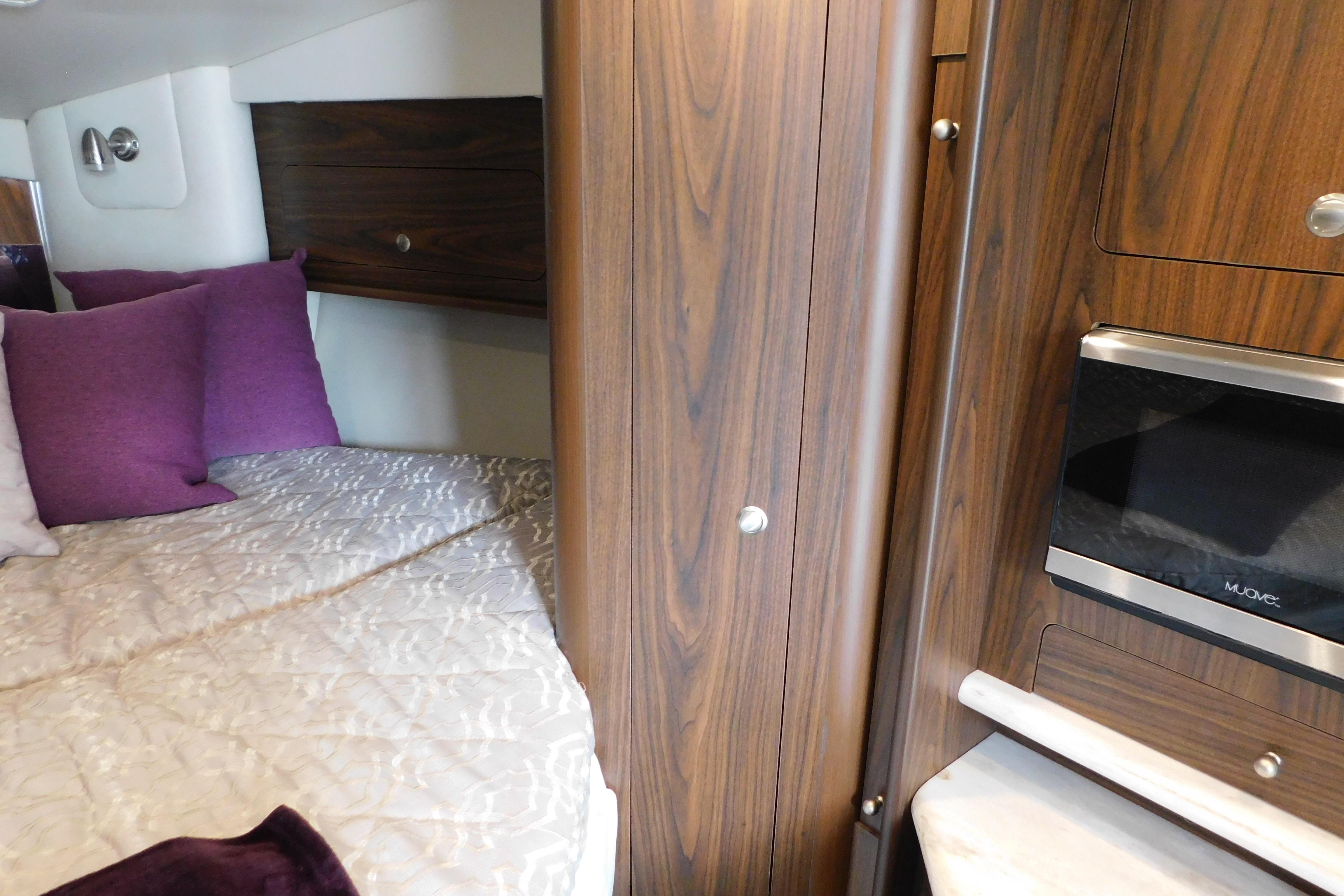Interior cabin of 2017 Rinker EX 320 with bed, pillows, and wood cabinetry.