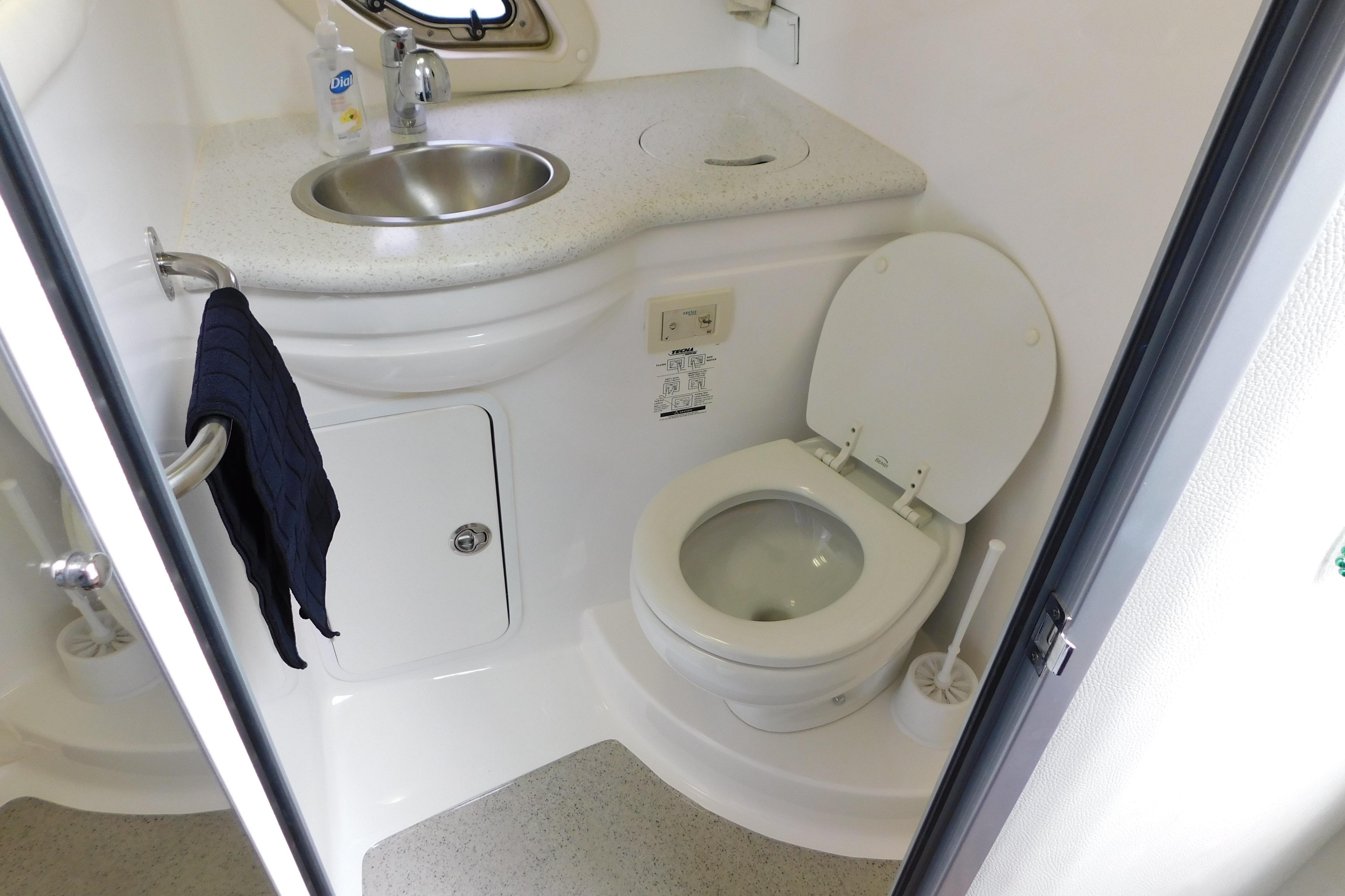 Compact bathroom in 2017 Rinker EX 320 boat with sink and toilet.