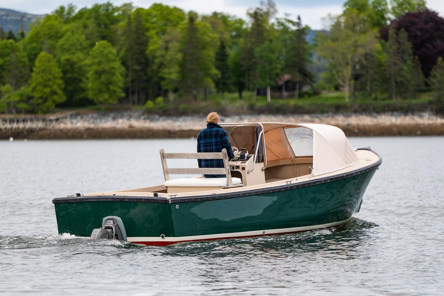 1989 Ellis 24 Open boat cruising on a calm lake with lush green trees.