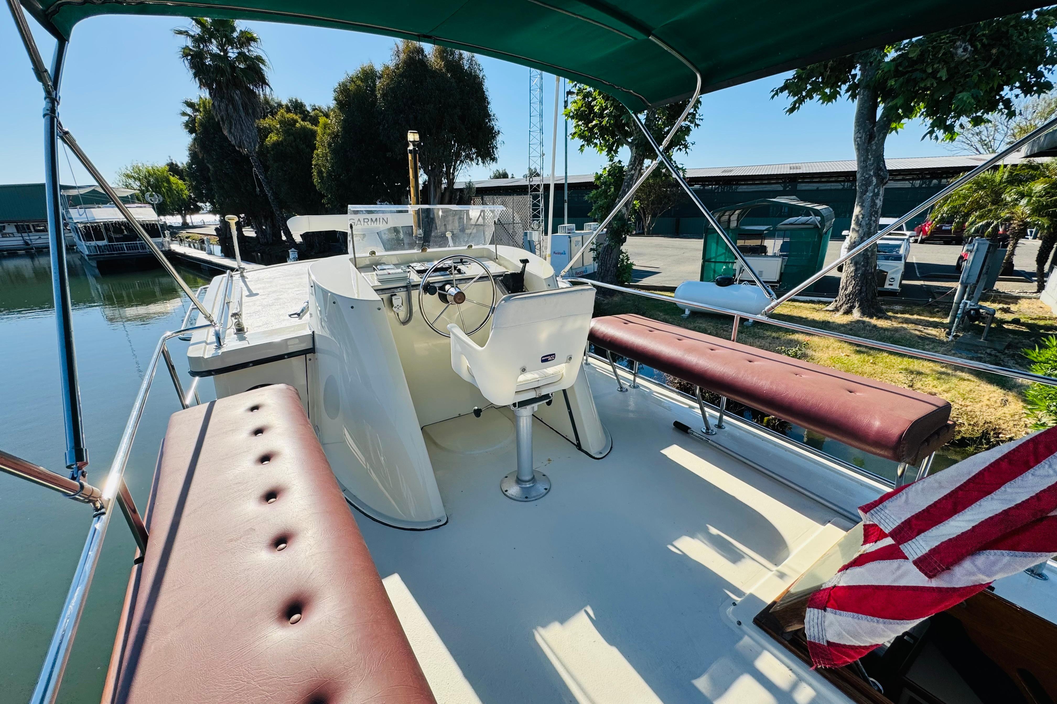 1996 Nordic Tug 32 boat deck with seating, steering wheel, and American flag.