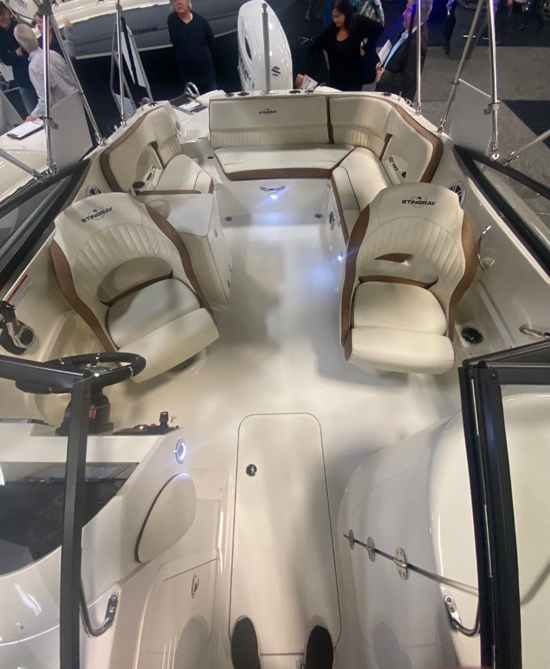 Interior view of a modern boat with white leather seats and steering wheel.