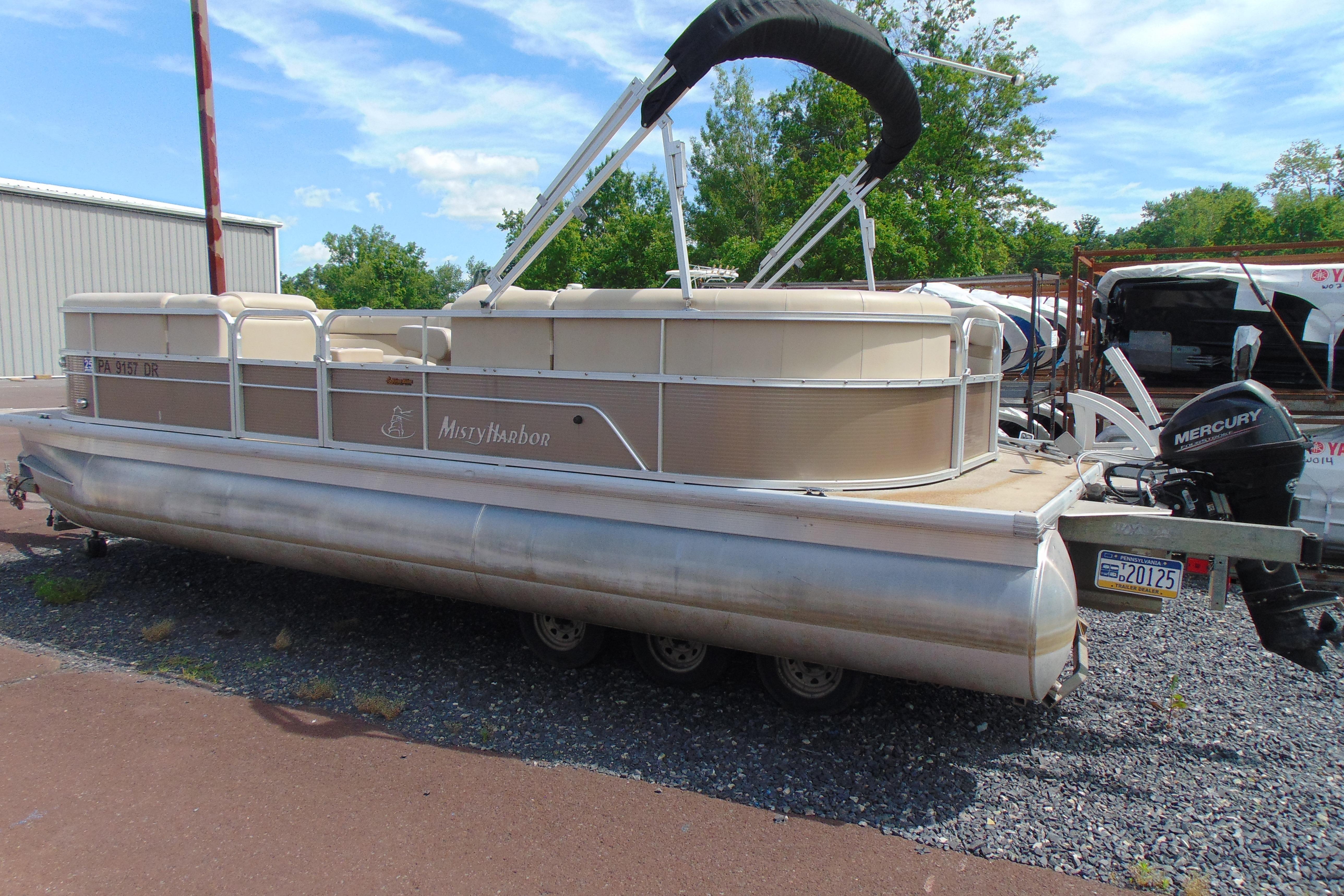 2016 Misty Harbor 245 Adventure CU pontoon boat with Mercury outboard motor, parked outdoors.