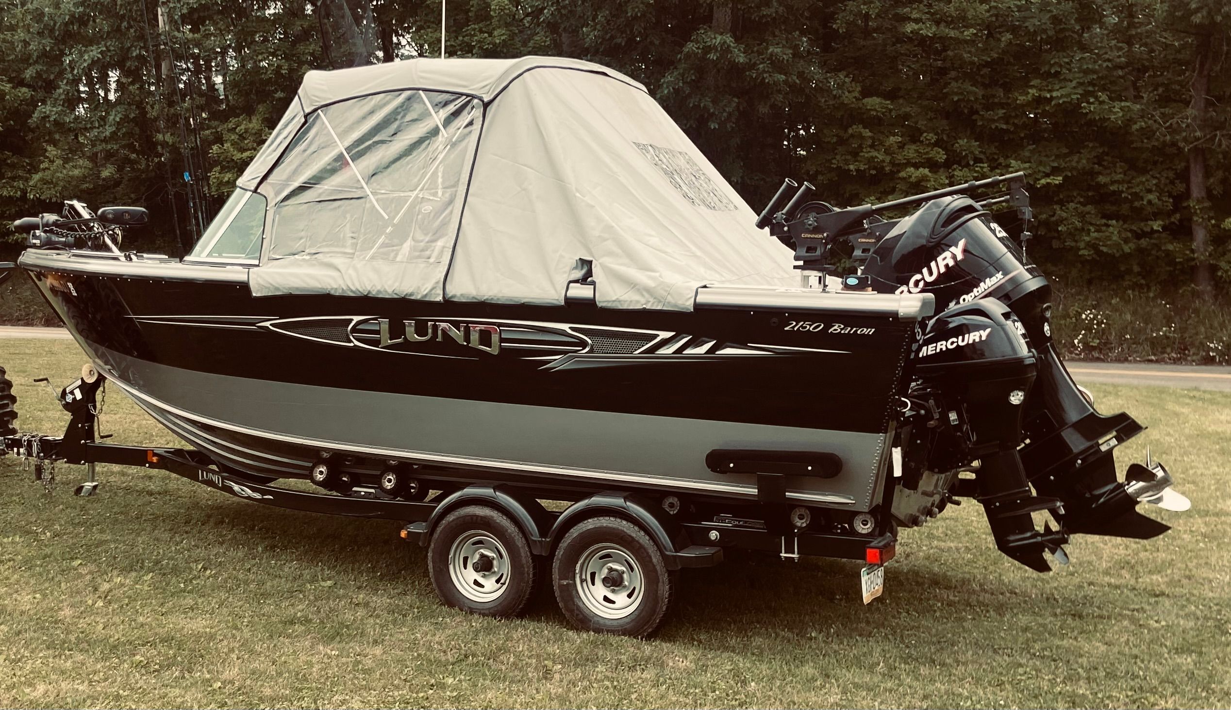 A 2012 Lund Baron boat is on a trailer on a grassy area.