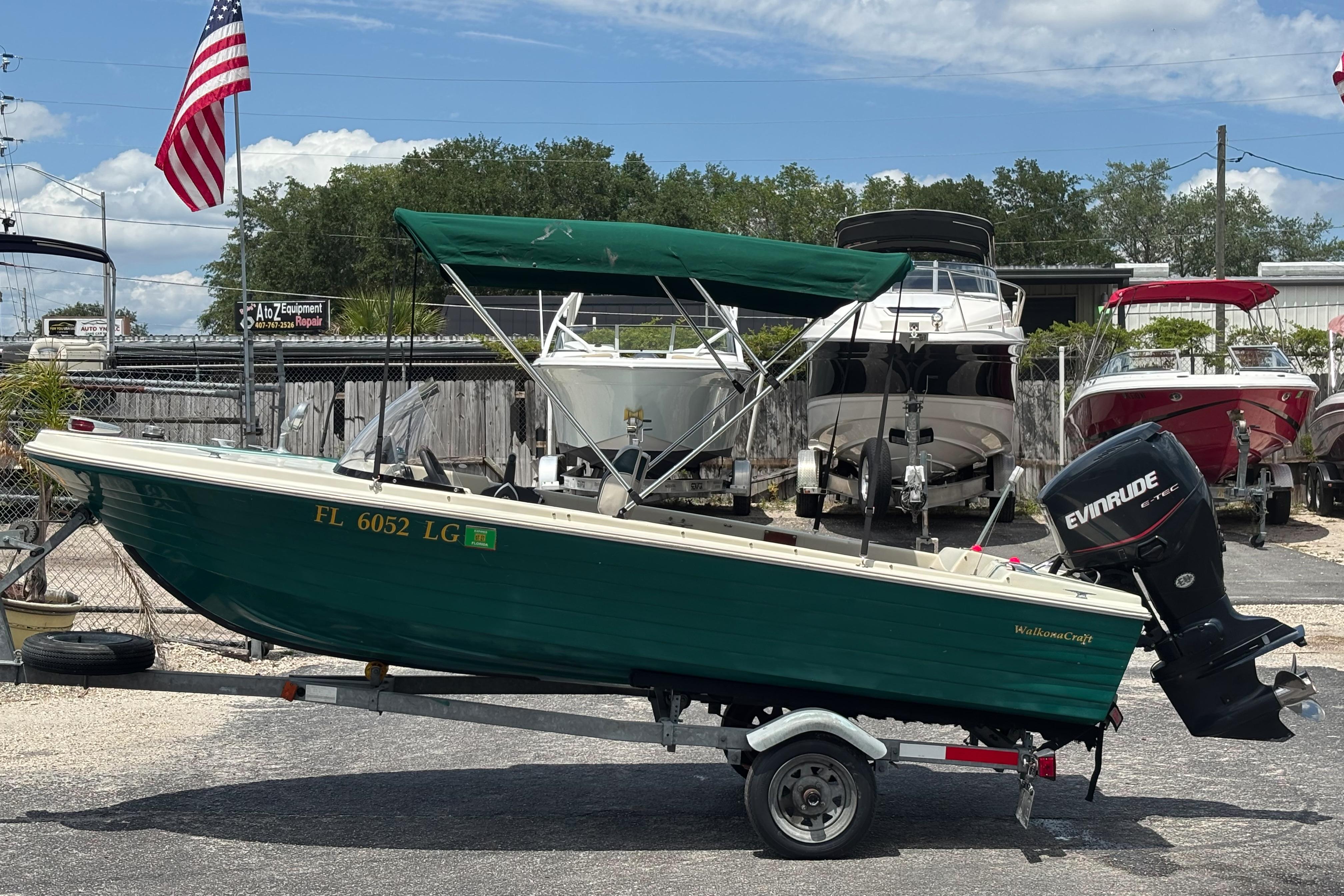 1966 Mohawk 15 boat with green canopy on trailer, parked near other boats.