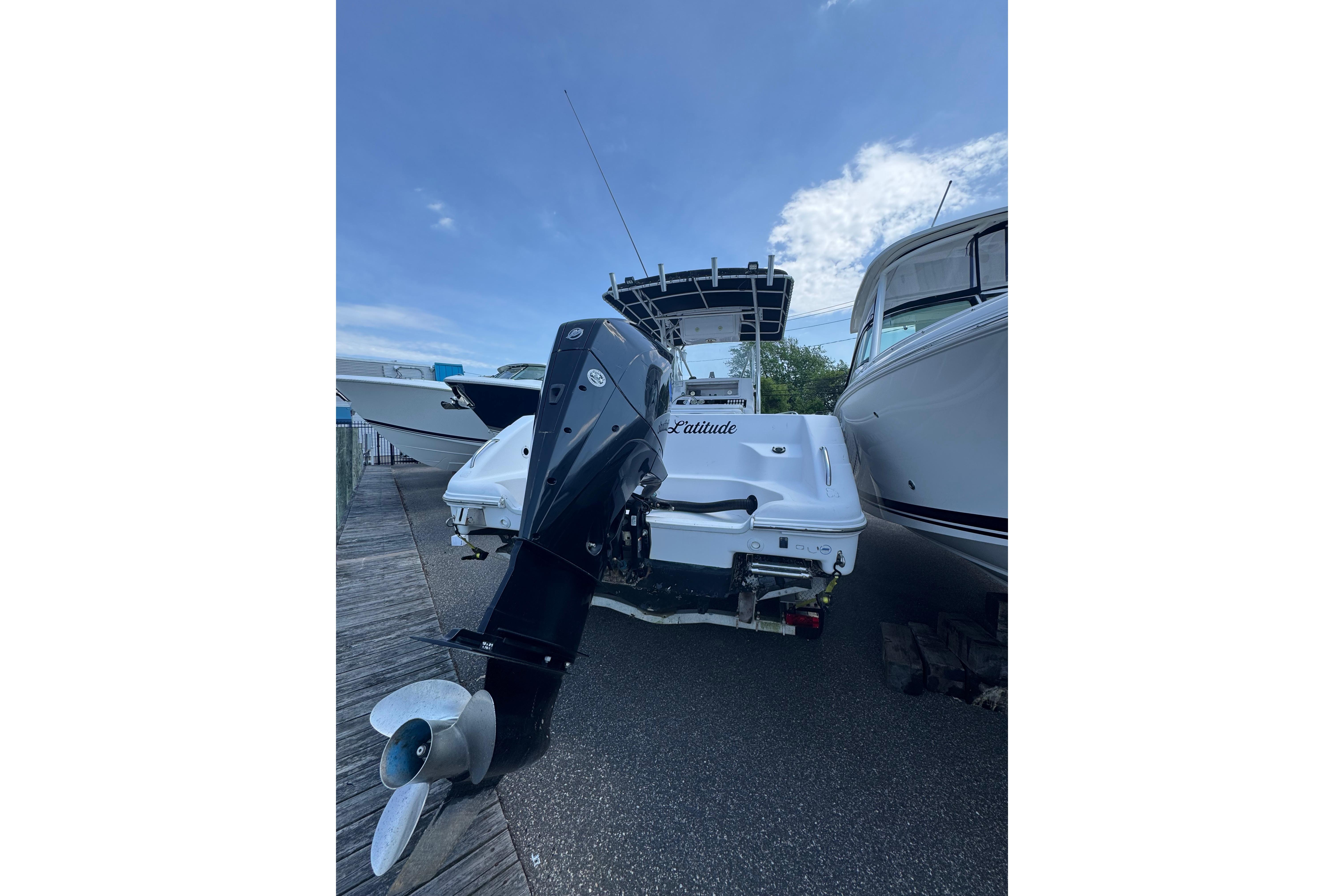 2002 Pro-Line 23 Sport boat with outboard motor, docked between other vessels.