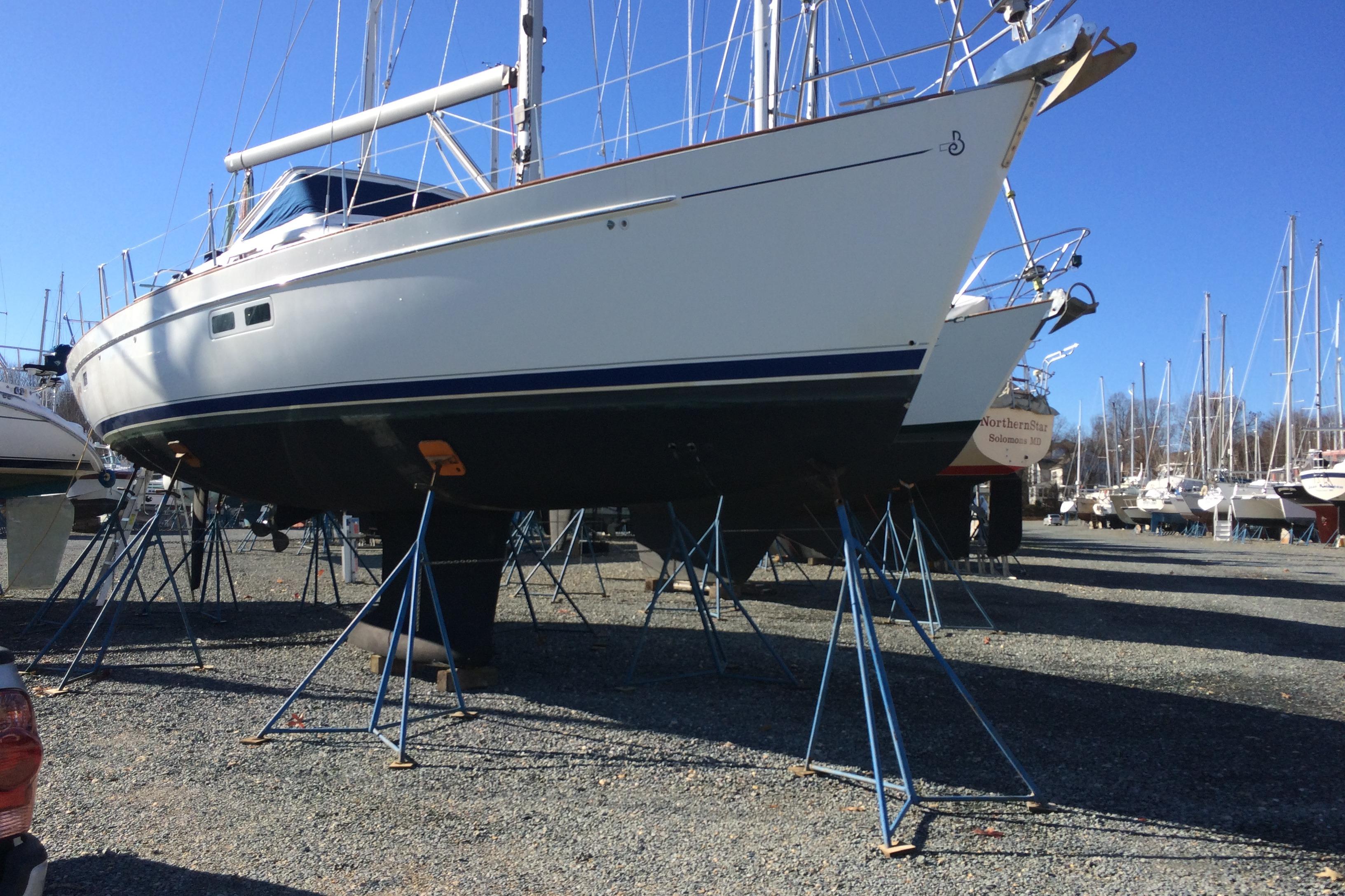 2003 Beneteau Oceanis 42CC sailboat on stands in a boatyard under clear blue sky.