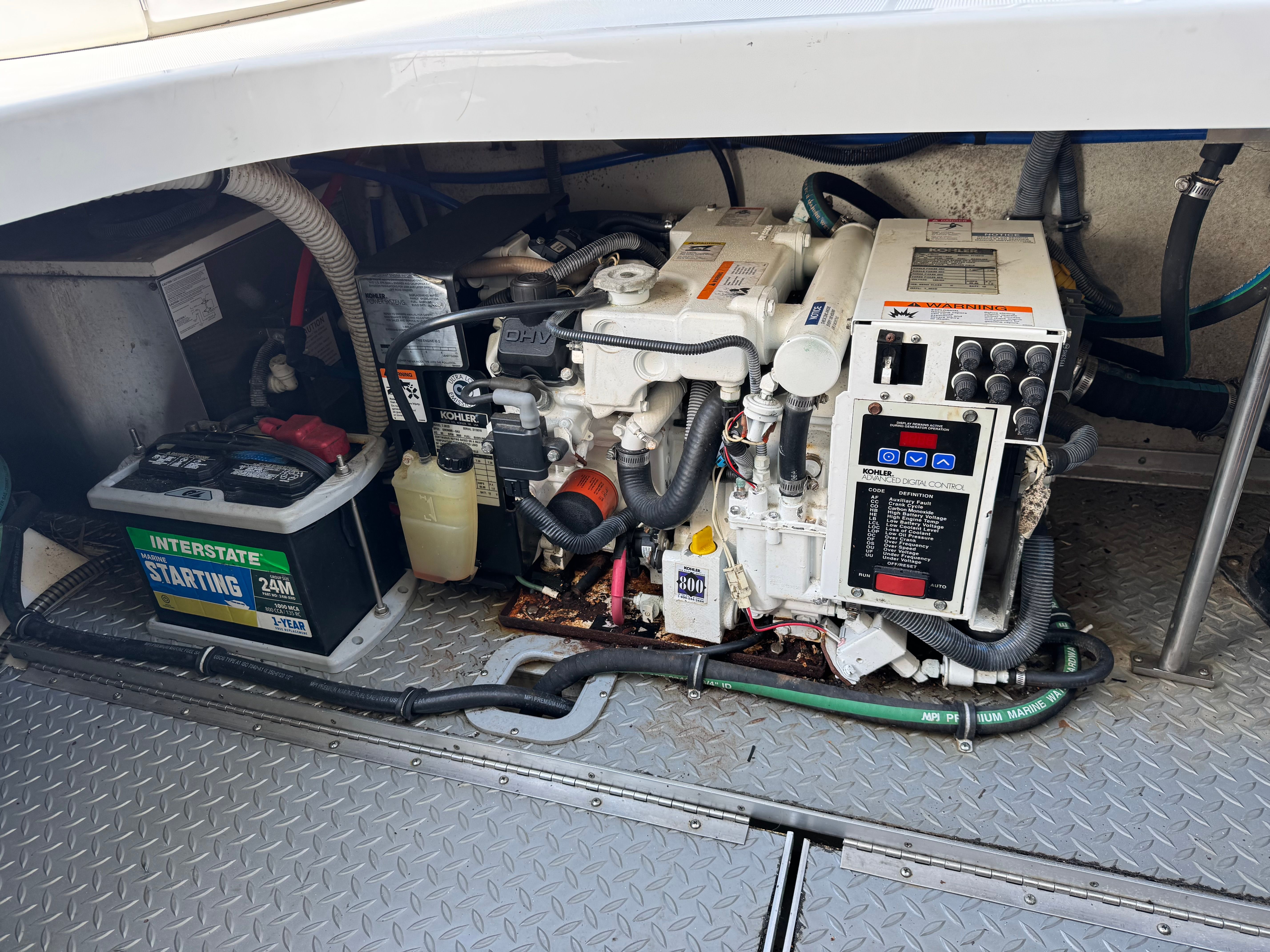 Engine compartment of a boat with generator and battery.