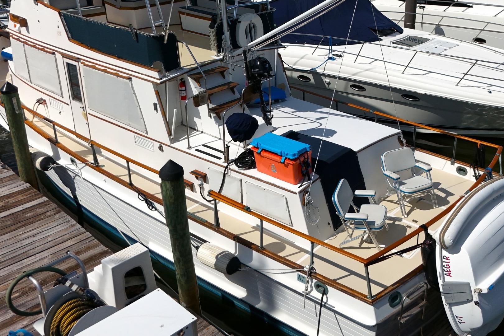 1978 Grand Banks 42 Classic yacht docked, featuring deck chairs and a cooler.