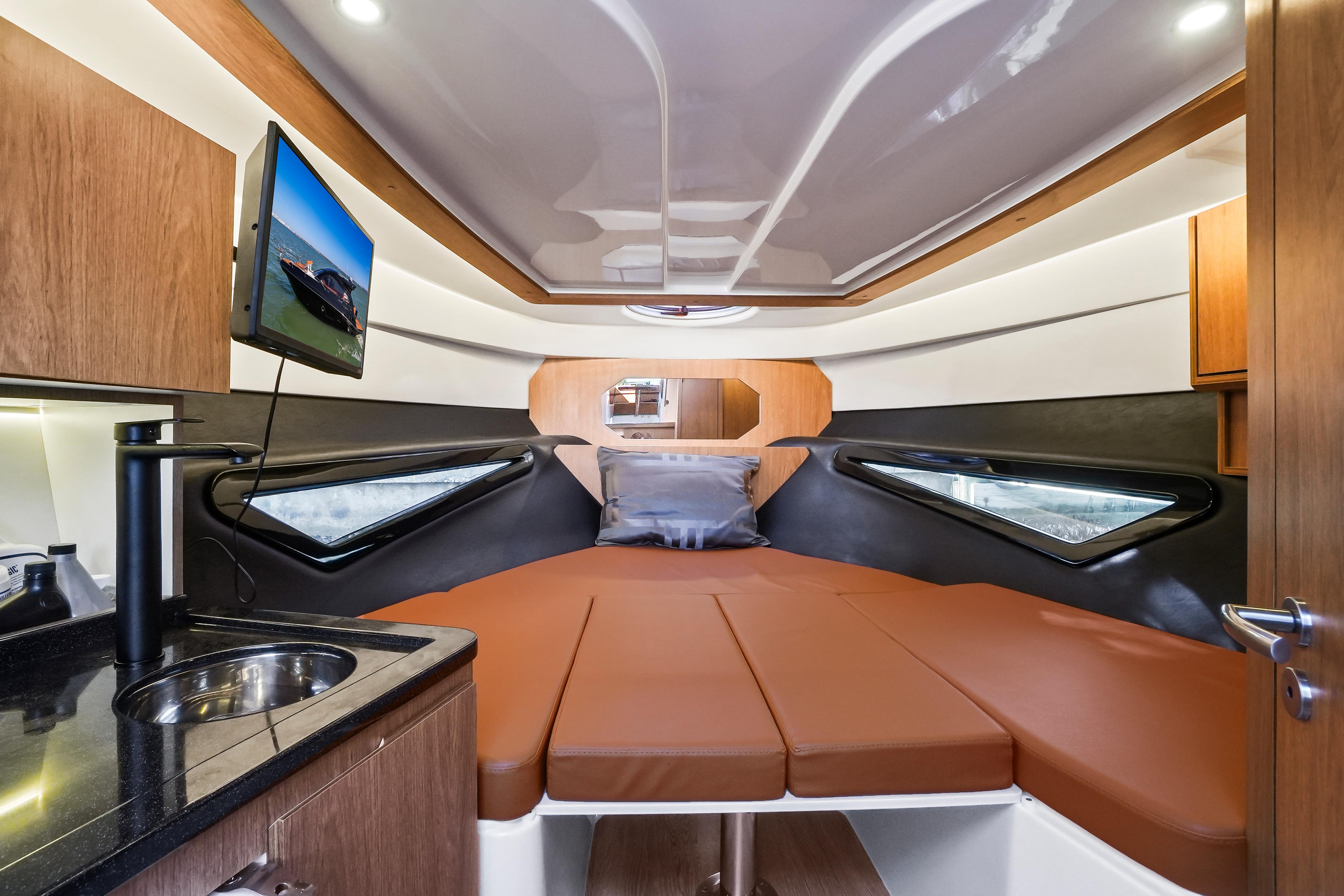 Luxurious interior of 2026 Hanover 355 boat with bed, TV, and kitchenette.