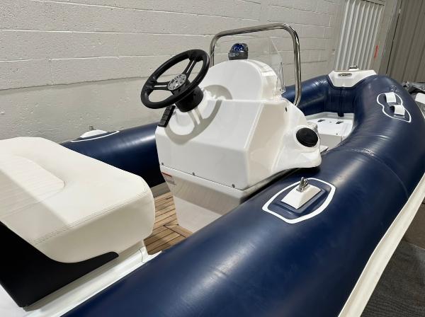 2024 Apex A-13 Deluxe Tender boat with blue and white design, featuring steering console and seating.