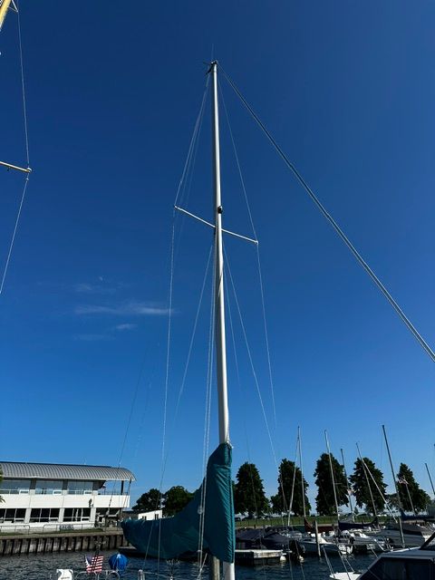 A 1985 Catalina 27 sailboat with a tall mast in a marina.