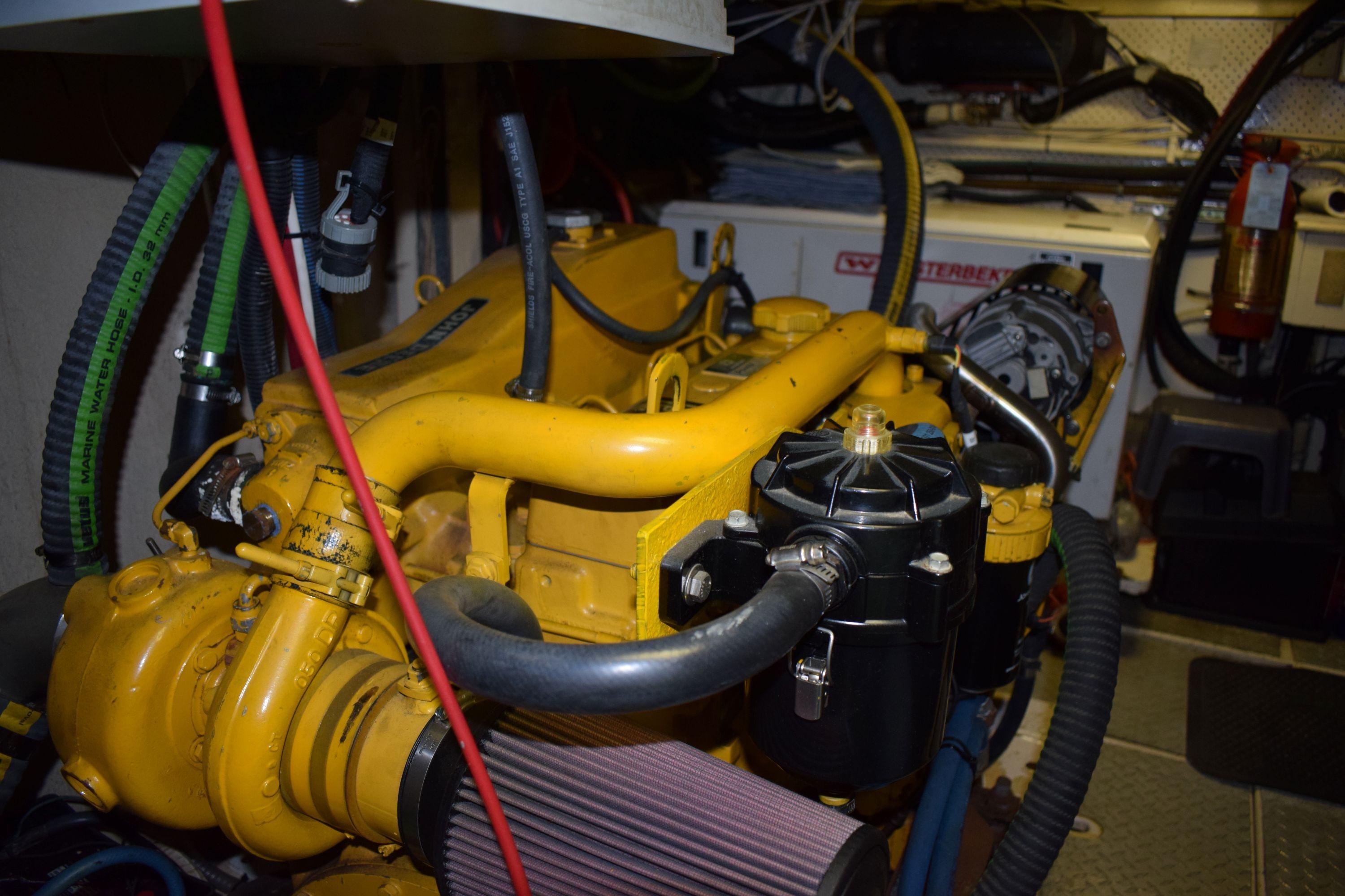 Engine room of 1980 Cheoy Lee 52 Motorsailer with visible yellow machinery and hoses.