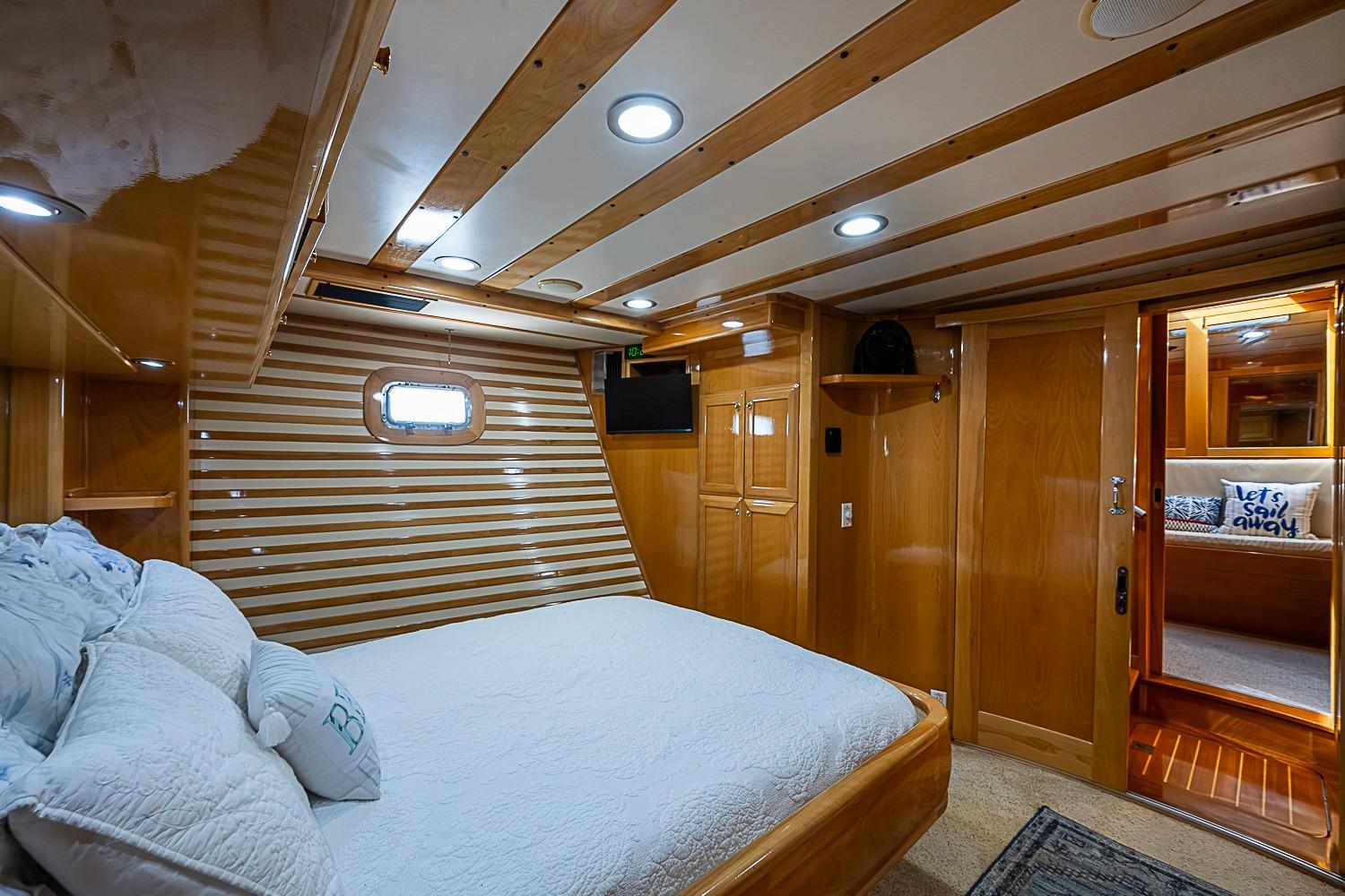 Luxurious cabin interior of 2003 Magna Marine Nova Scotia 47 yacht, featuring wood paneling and cozy bedding.